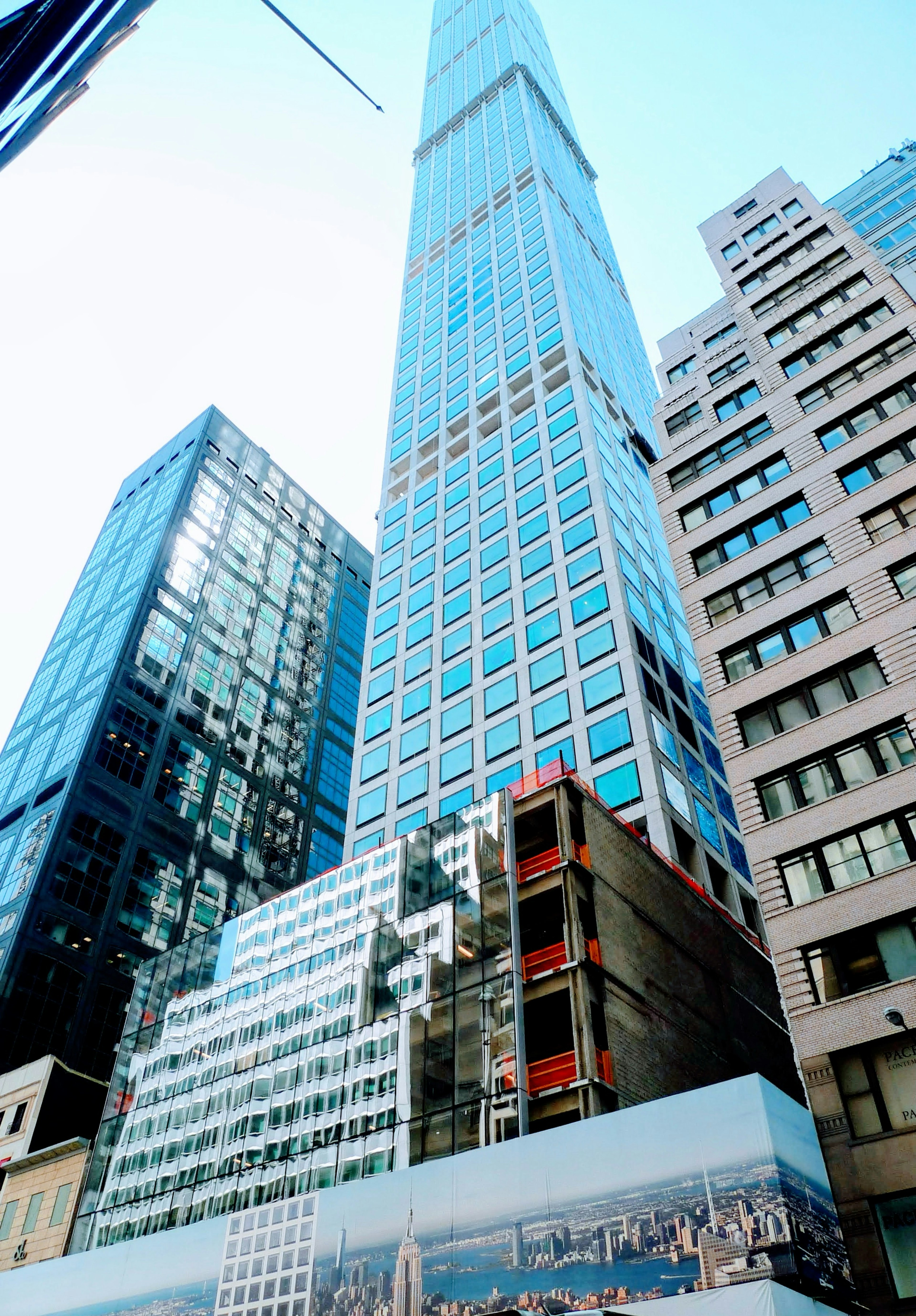 Modern glass skyscraper surrounded by urban buildings