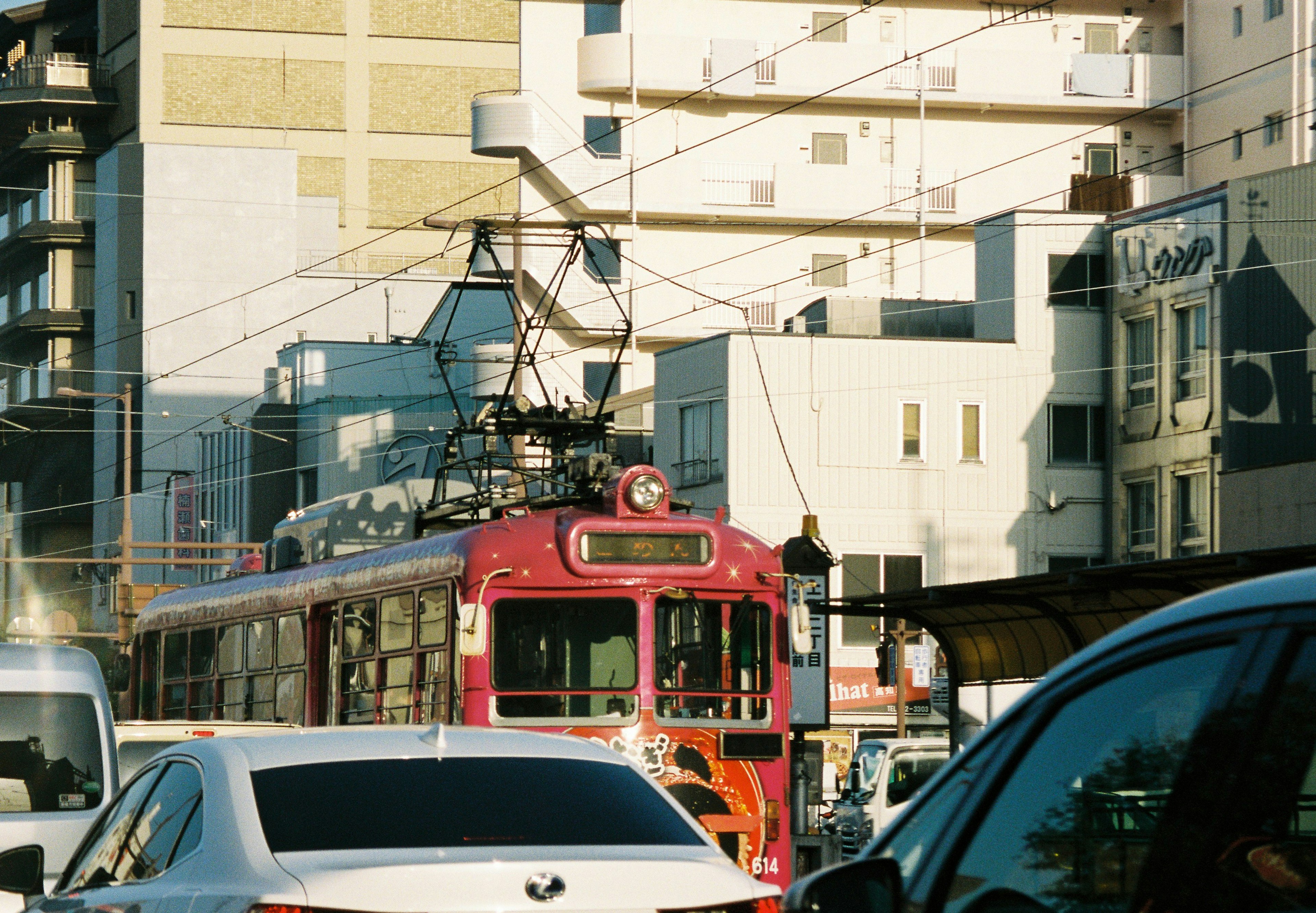 A red streetcar navigating through a busy urban street