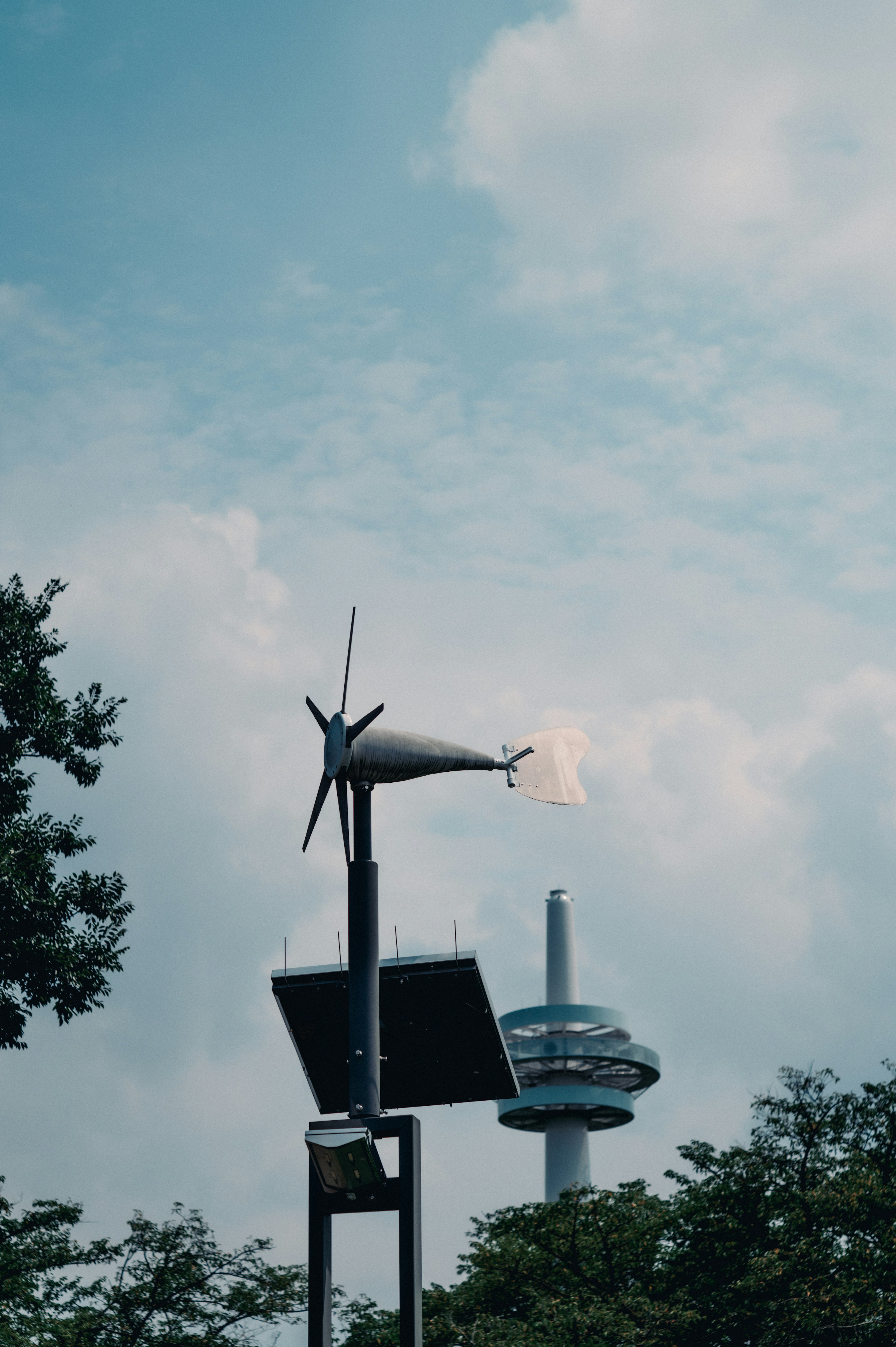 Paisaje con un aerogenerador y un panel solar con una torre plateada y cielo azul