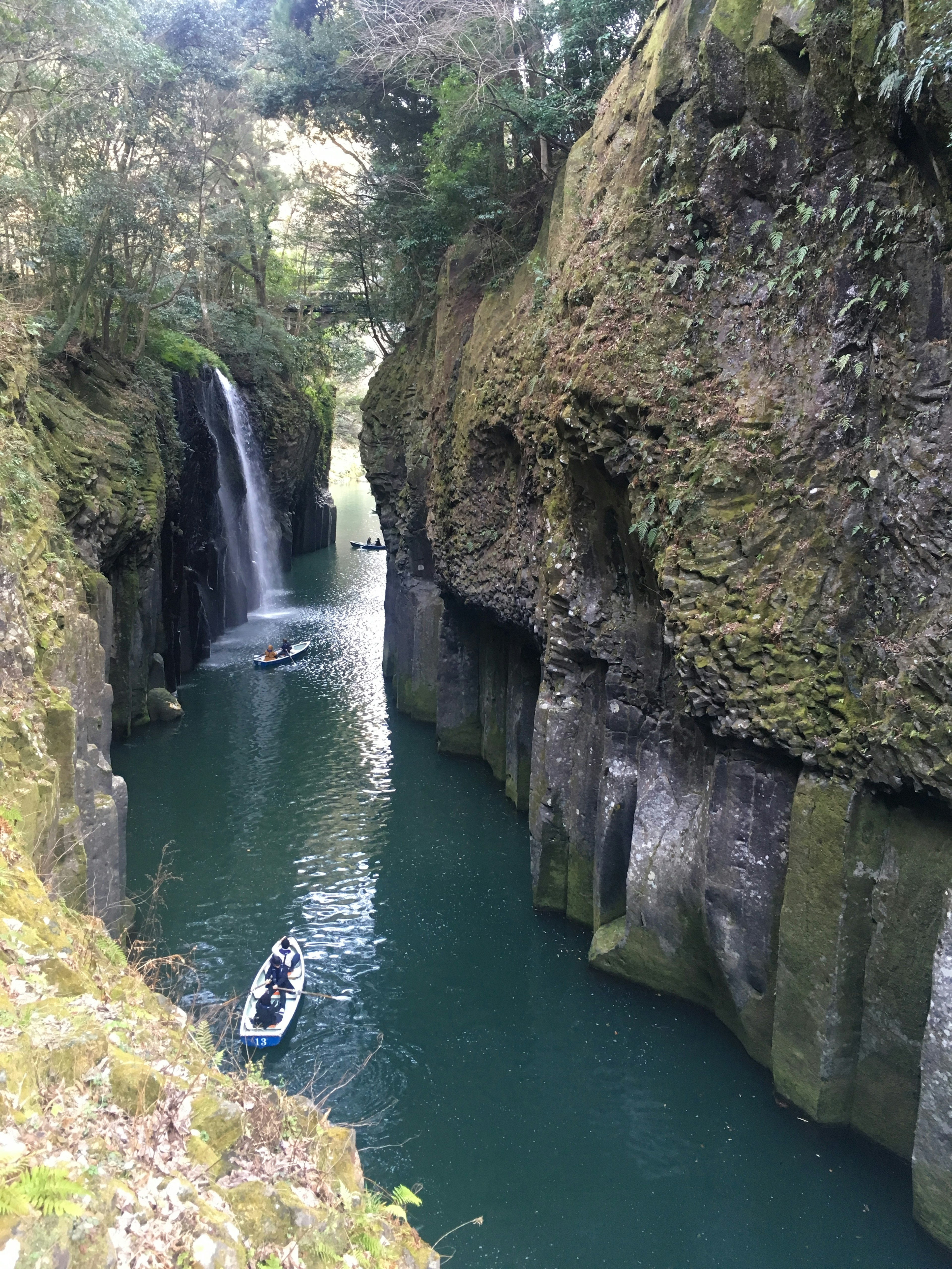 Ein üppiger grüner Canyon mit einem Wasserfall und einem ruhigen Fluss