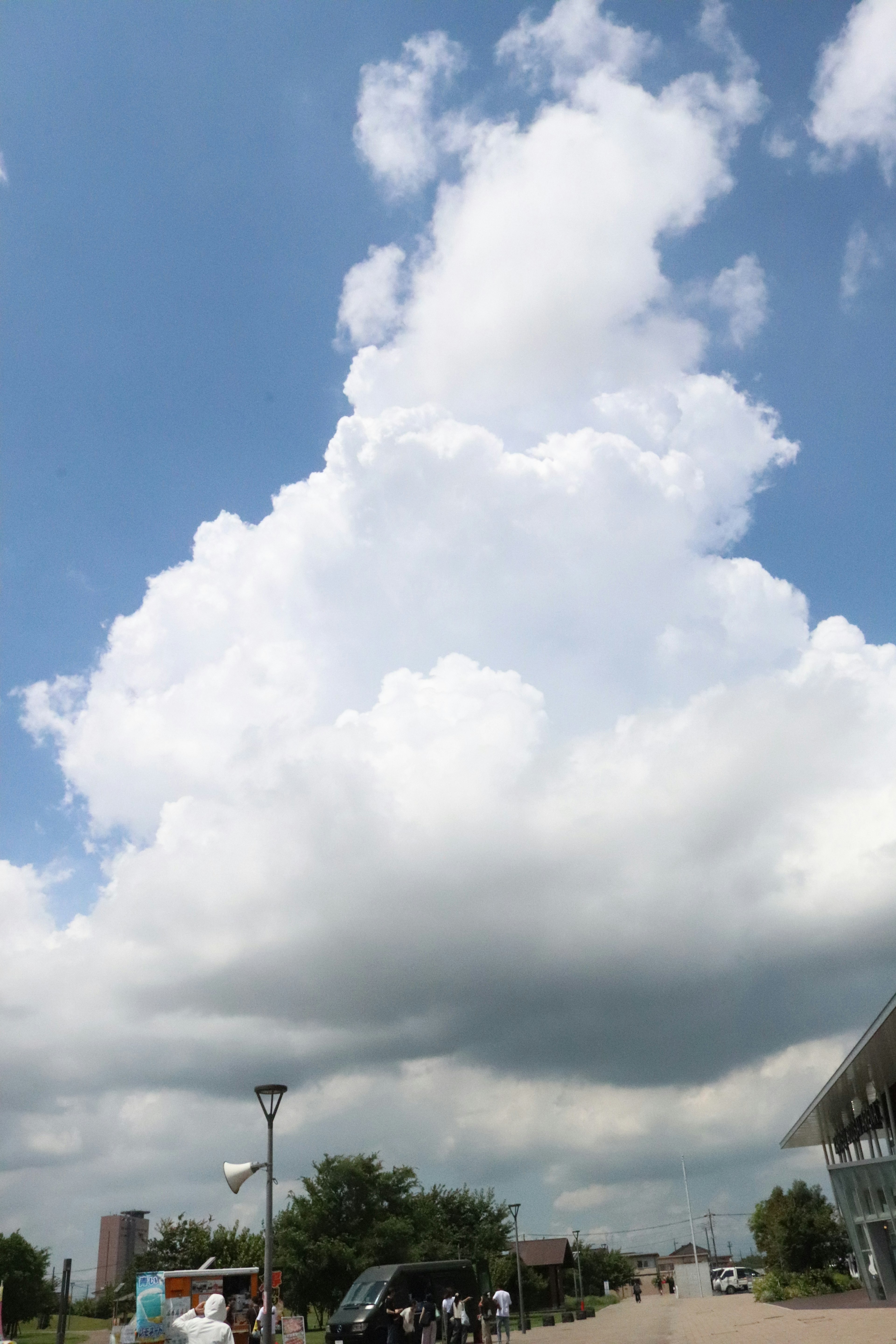 Large white clouds in a blue sky with green trees below