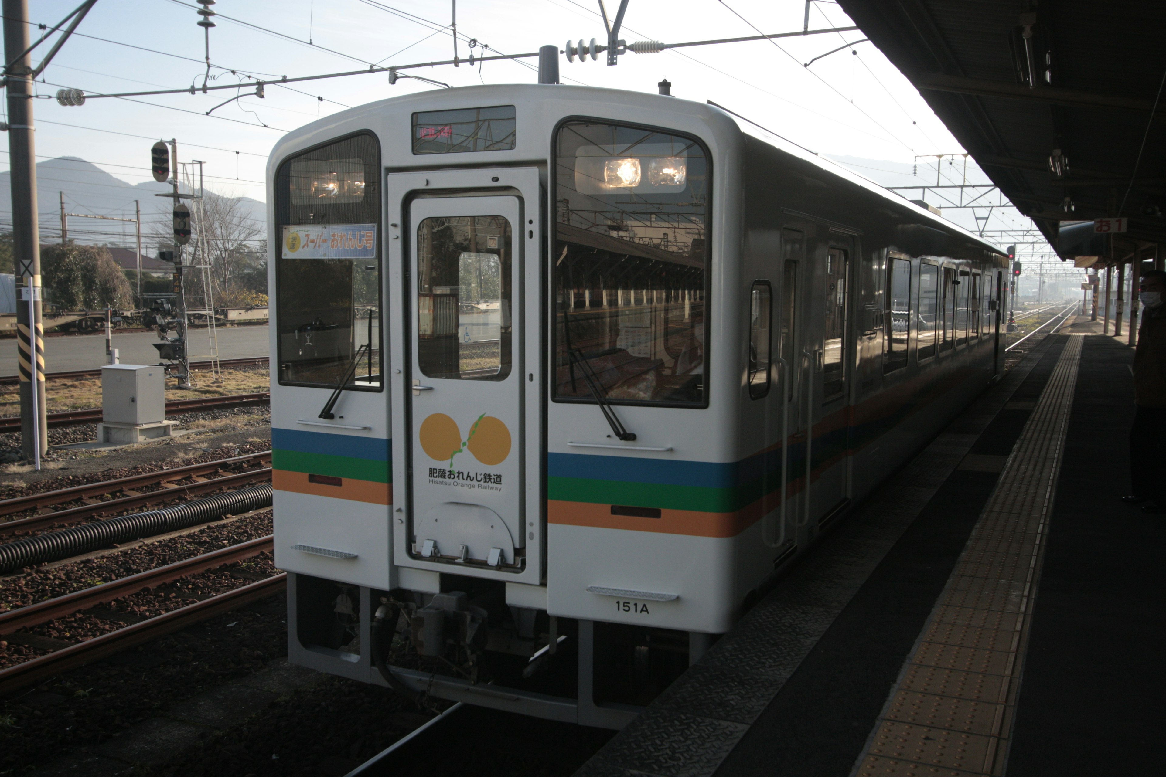 白い電車が駅のプラットフォームに停車している風景