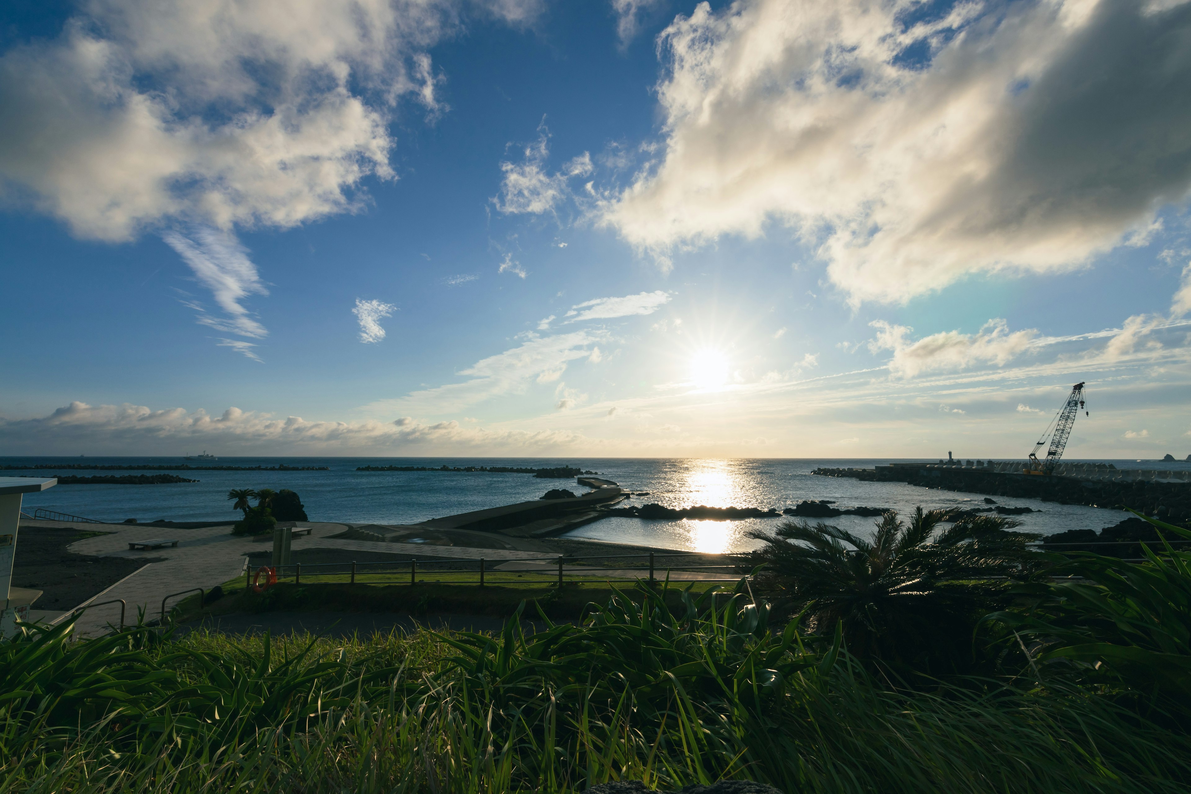 Scenic view of the ocean under a blue sky with clouds reflecting the sunset on the water