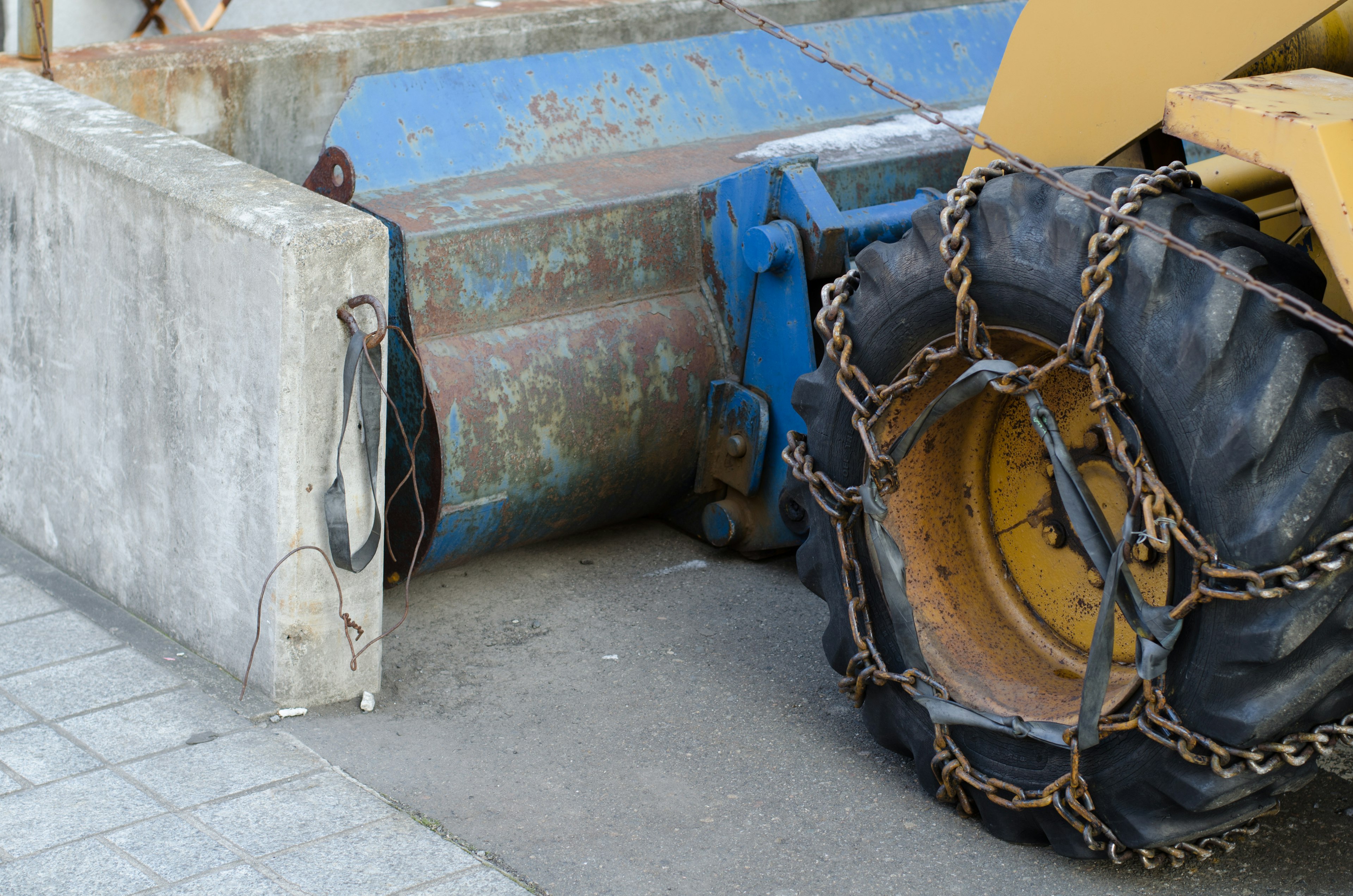 Pneu de véhicule de construction jaune avec chaîne attachée à côté d'un bloc de béton sur un chantier