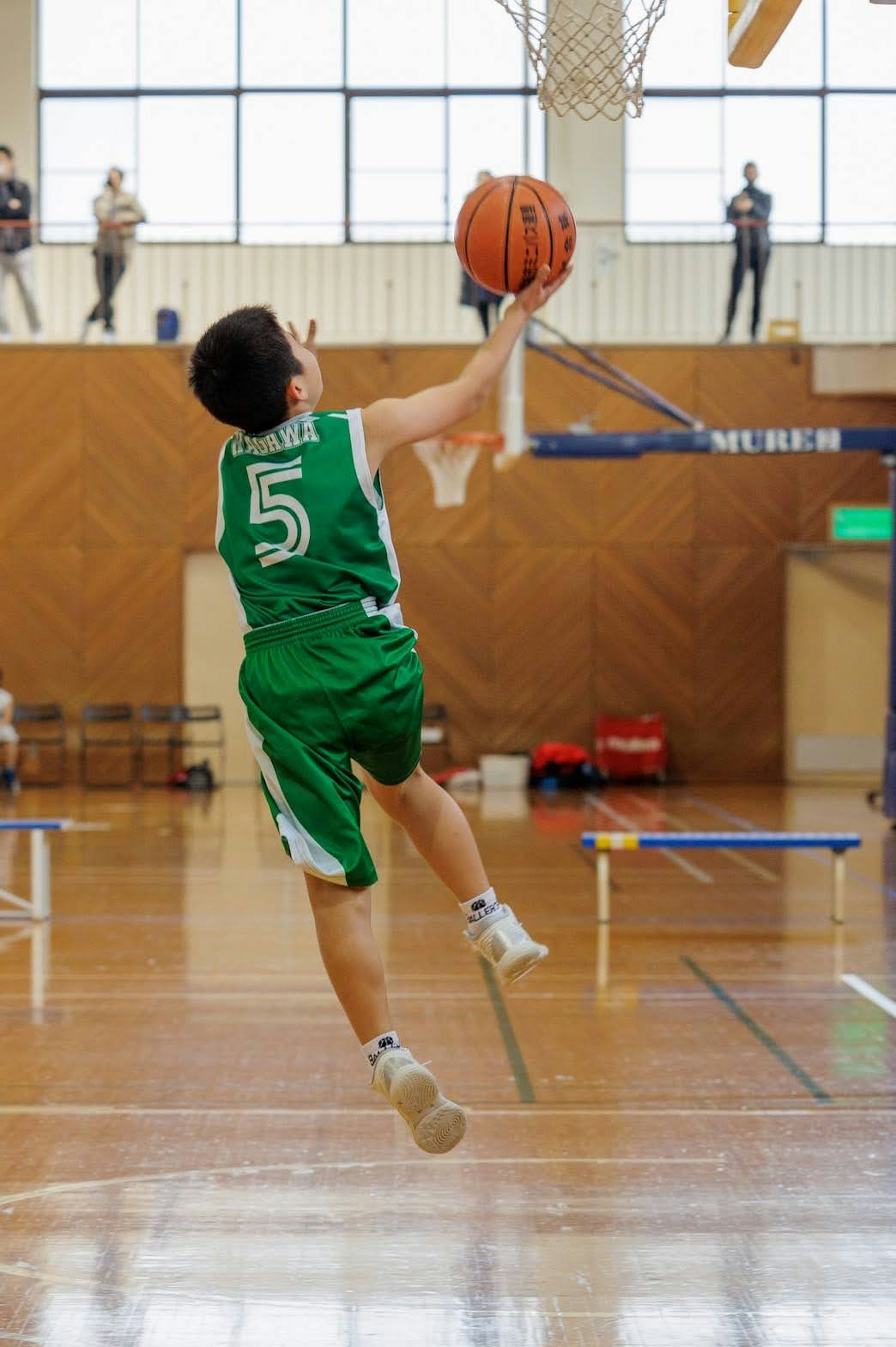 Basketballspieler versucht einen Dunk in grüner Uniform mit der Nummer 5