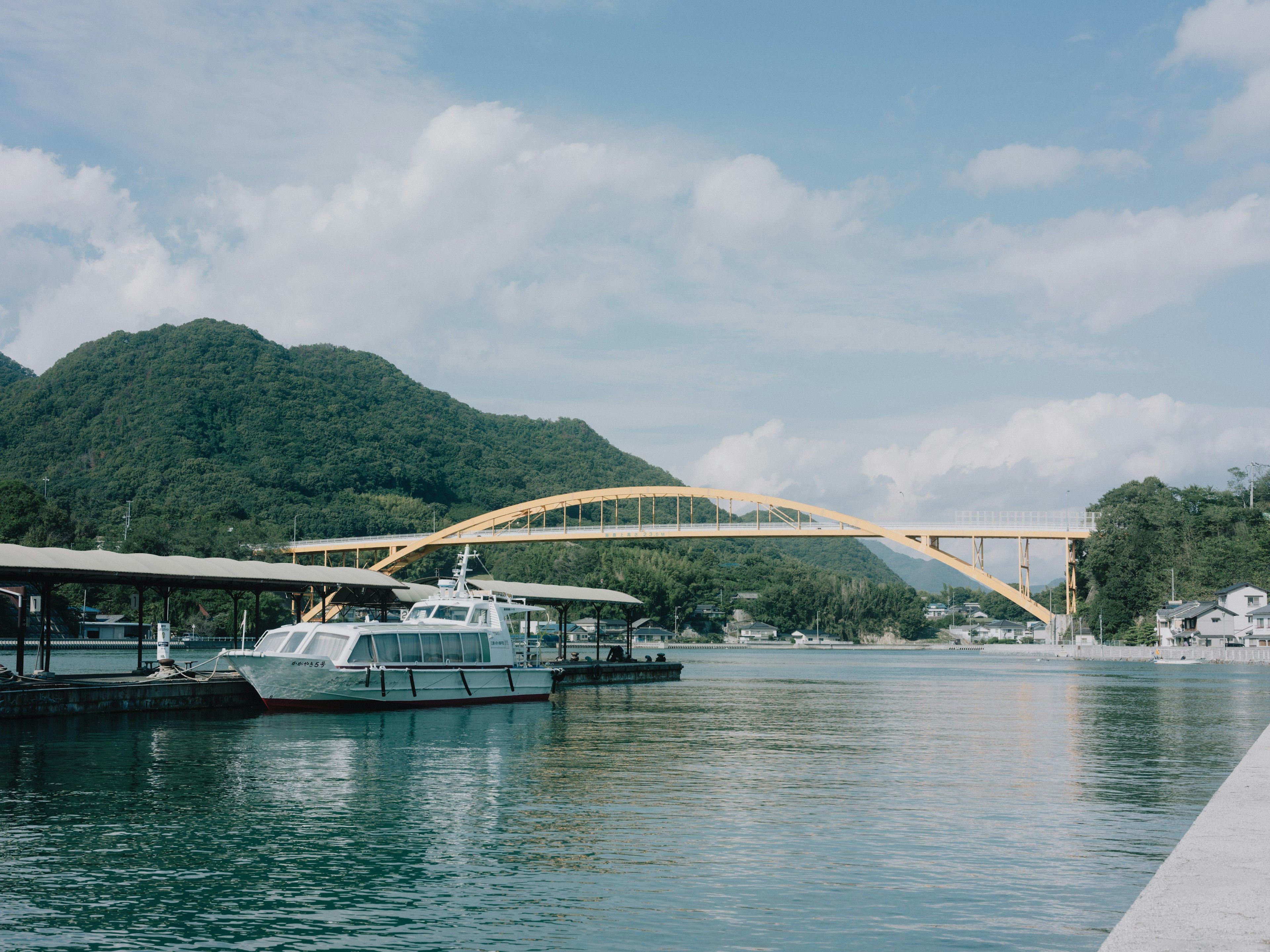 ทิวทัศน์แม่น้ำที่สวยงามมีสะพานโค้งสีเหลืองและเรือเงียบสงบ