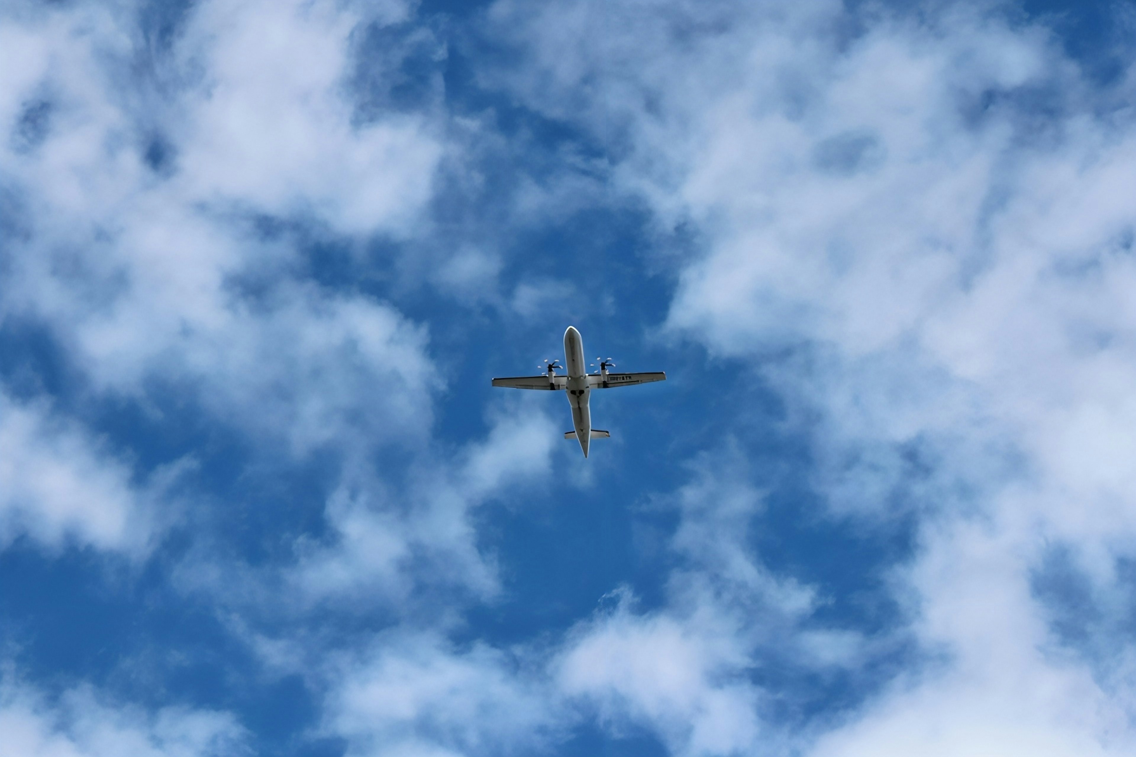 Avión volando en un cielo azul lleno de nubes