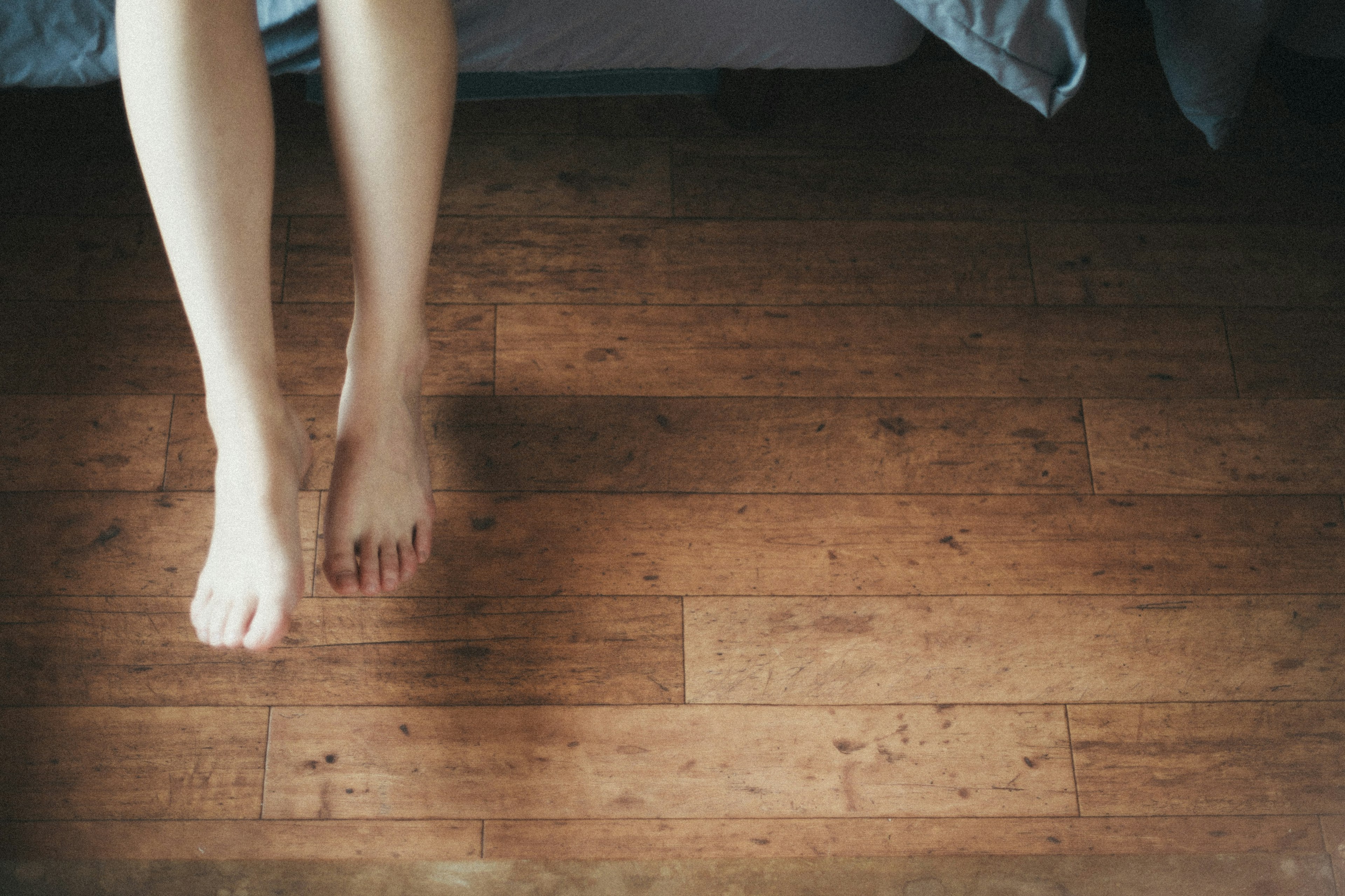 Kaki telanjang seorang wanita berdiri di samping tempat tidur