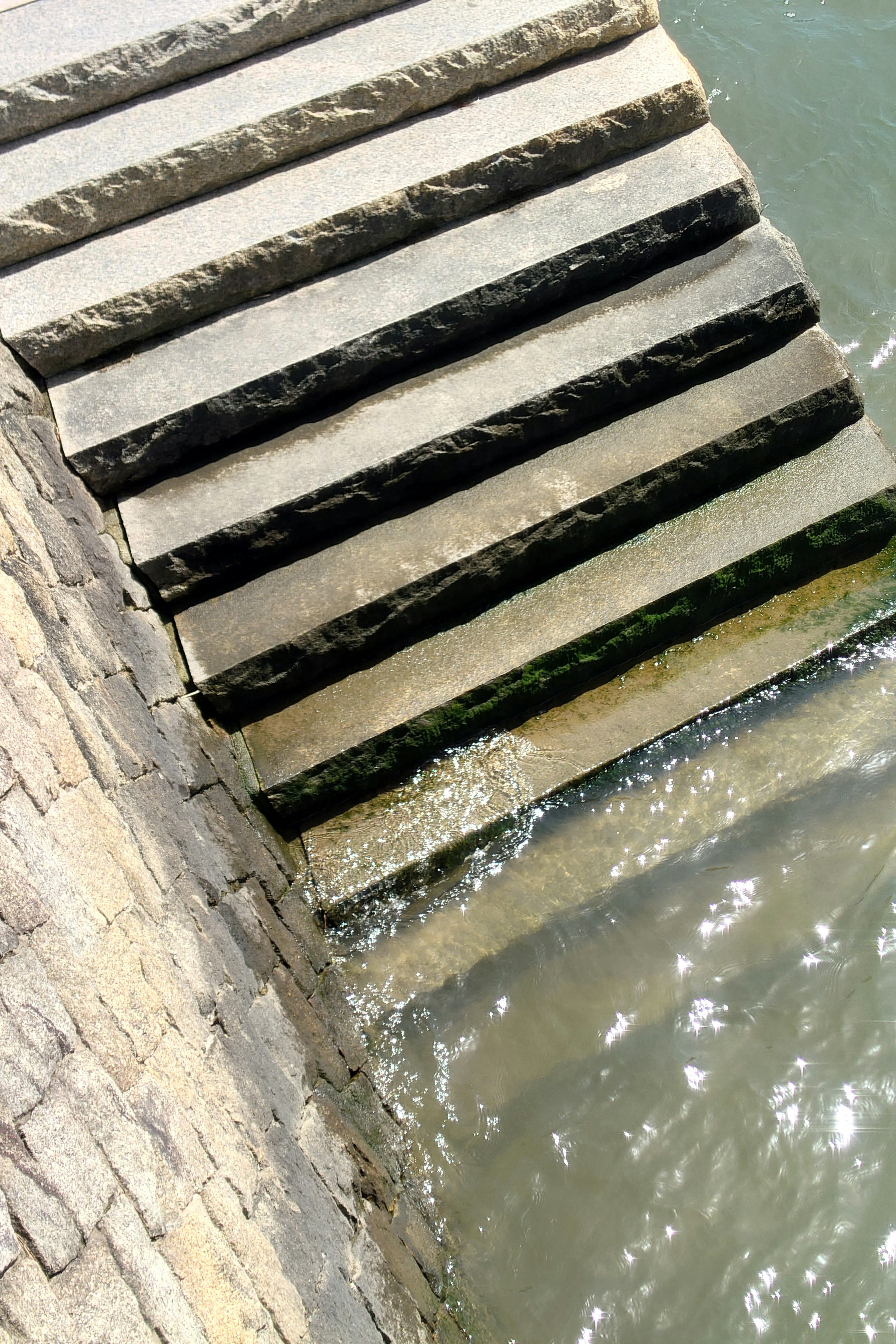 Image of stone steps leading into water with sunlight reflecting on the surface