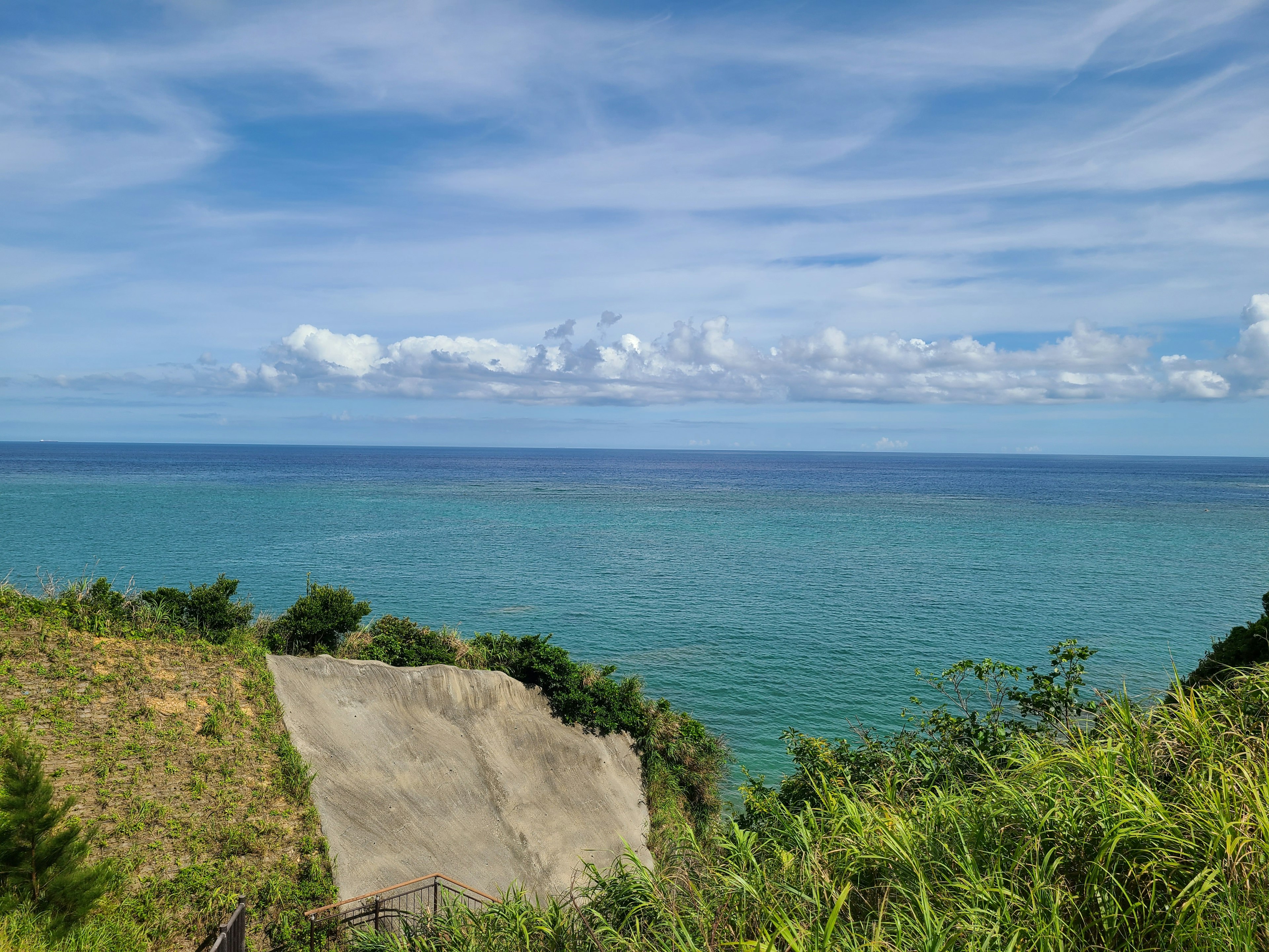 藍色海洋和天空的美麗景色，綠色山坡