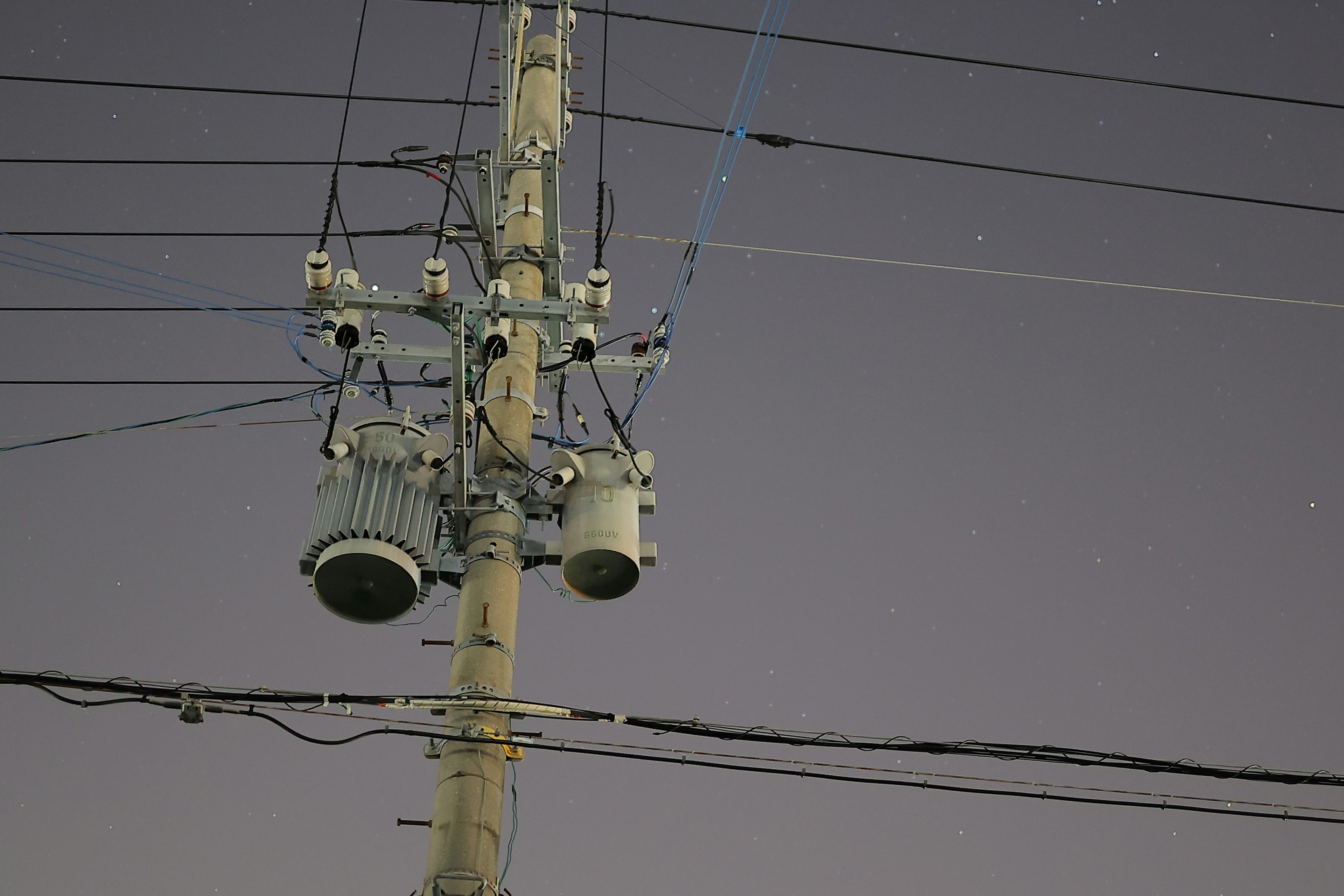 Vista nocturna de un poste de luz con cables eléctricos