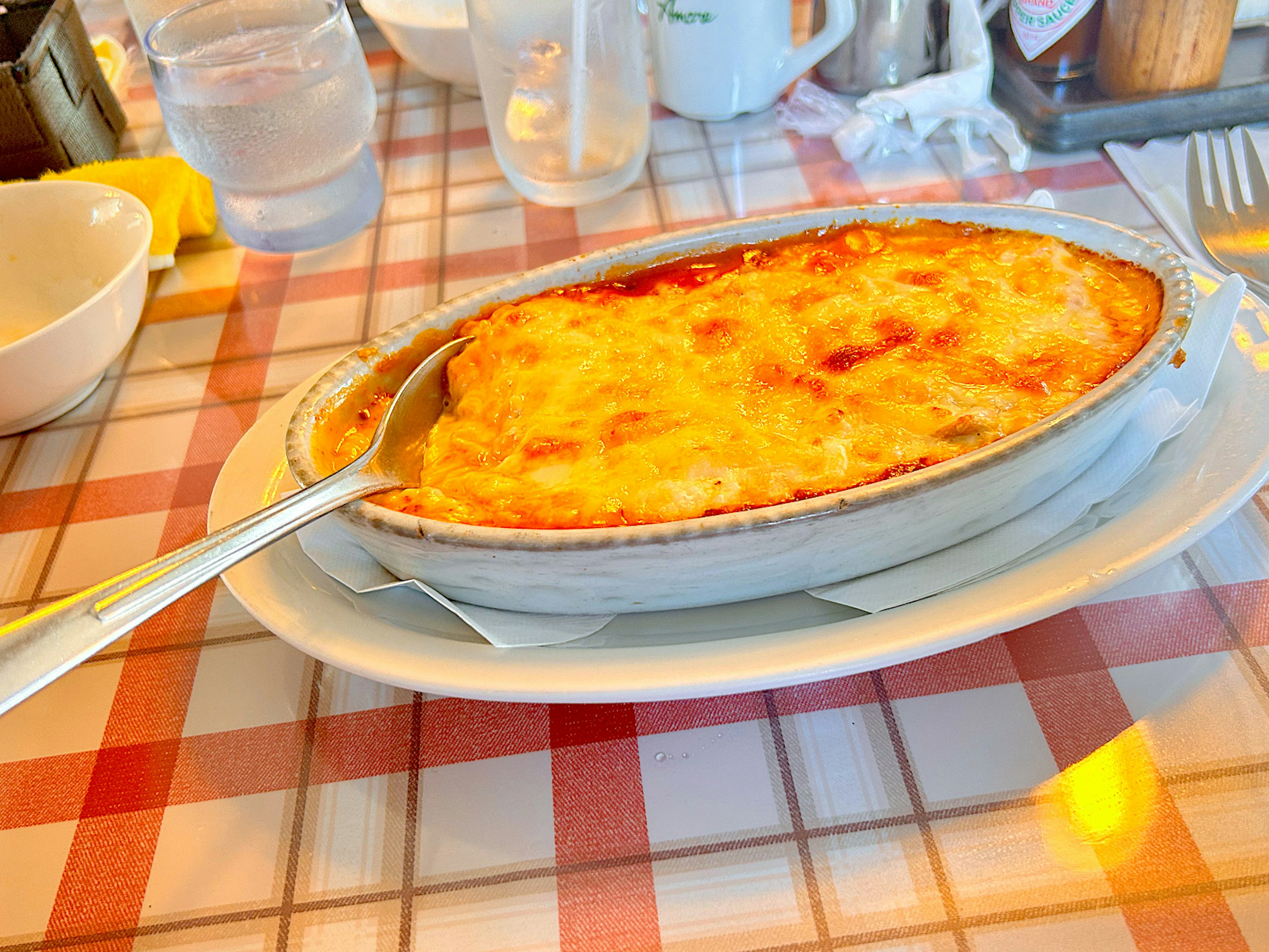 Gratin de macarrones cremoso cubierto con queso derretido servido en un plato