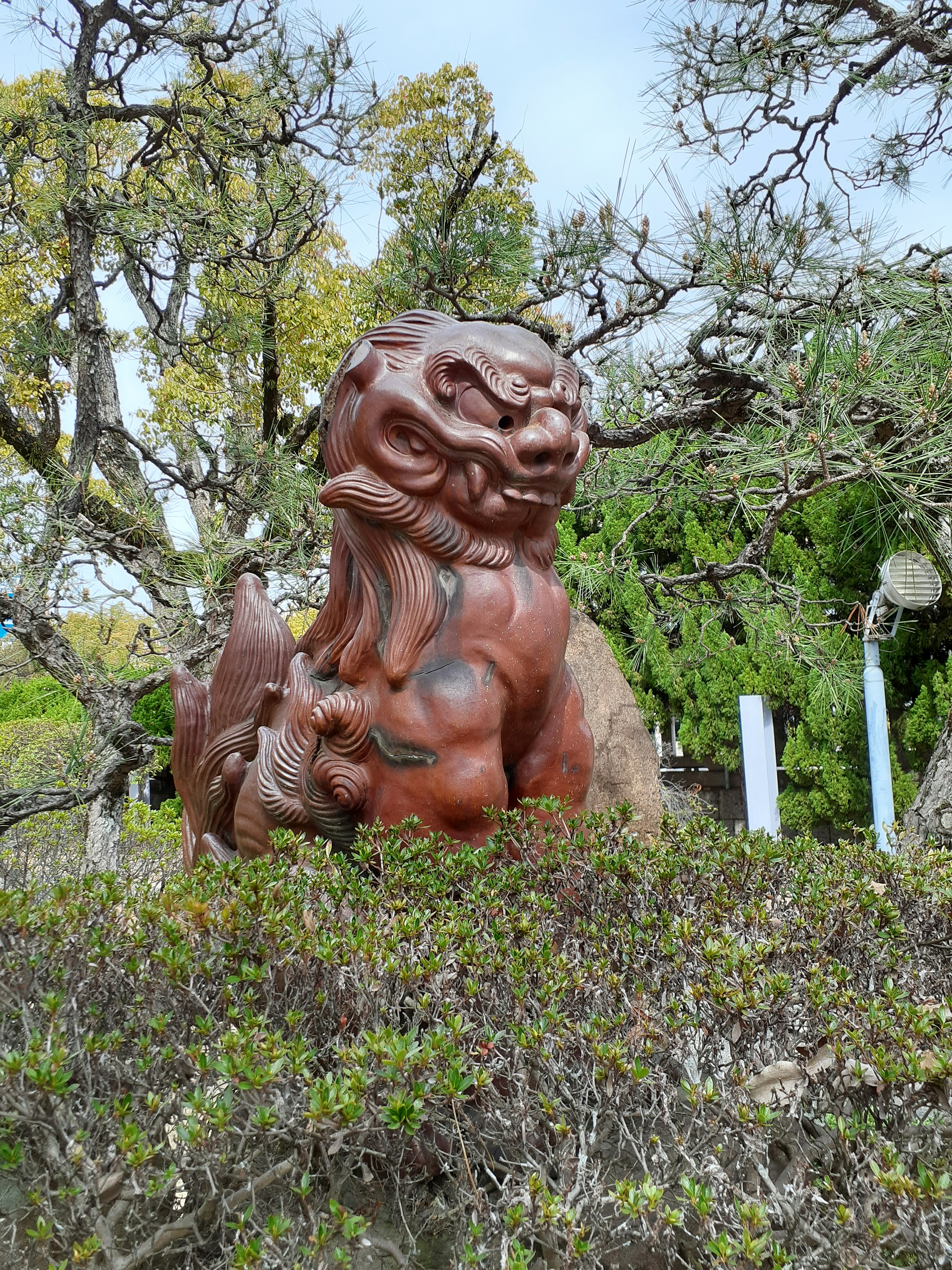 Scultura di leone rosso circondata da alberi verdi