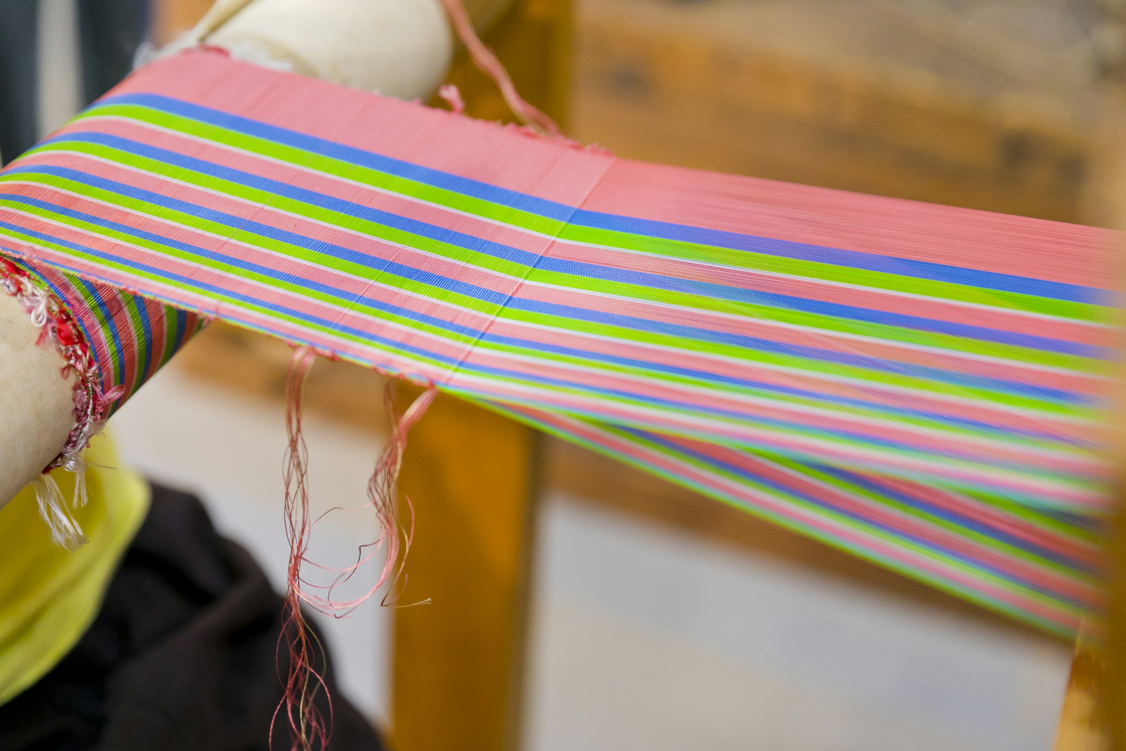 Colorful striped fabric being woven on a loom