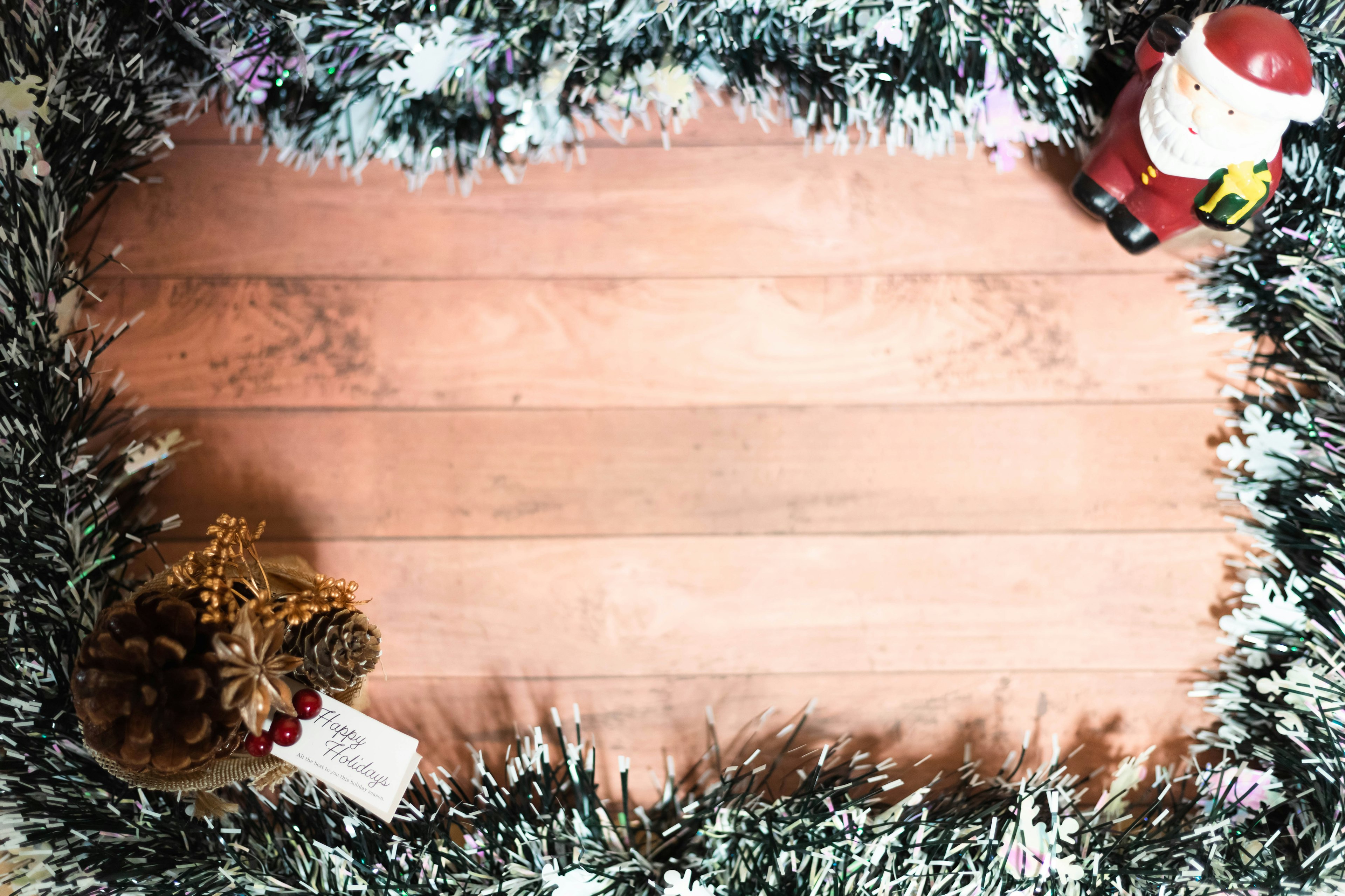 Decoración navideña con una figura de Santa y piñas en una mesa de madera