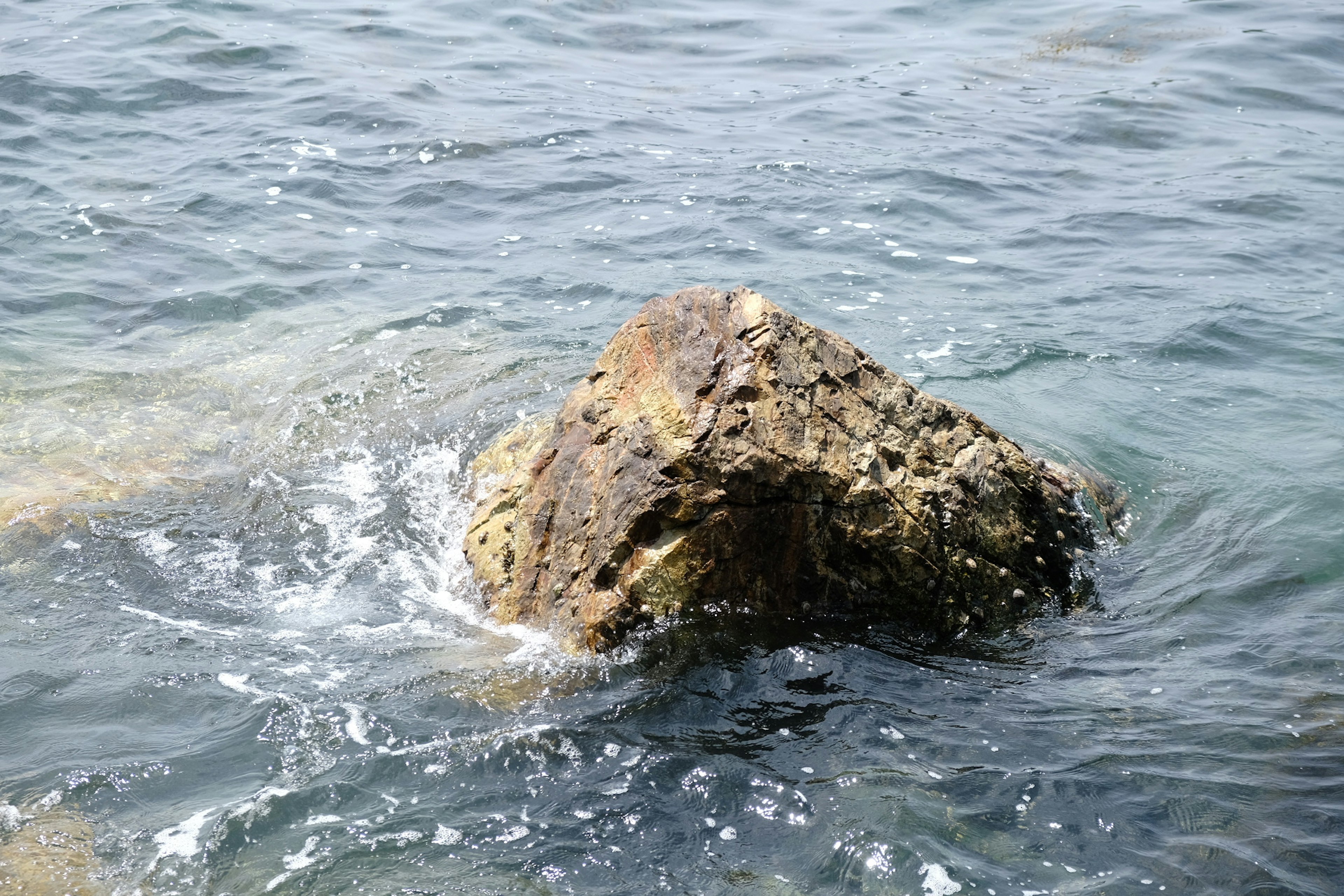 Una roca parcialmente sumergida en el agua con olas onduladas