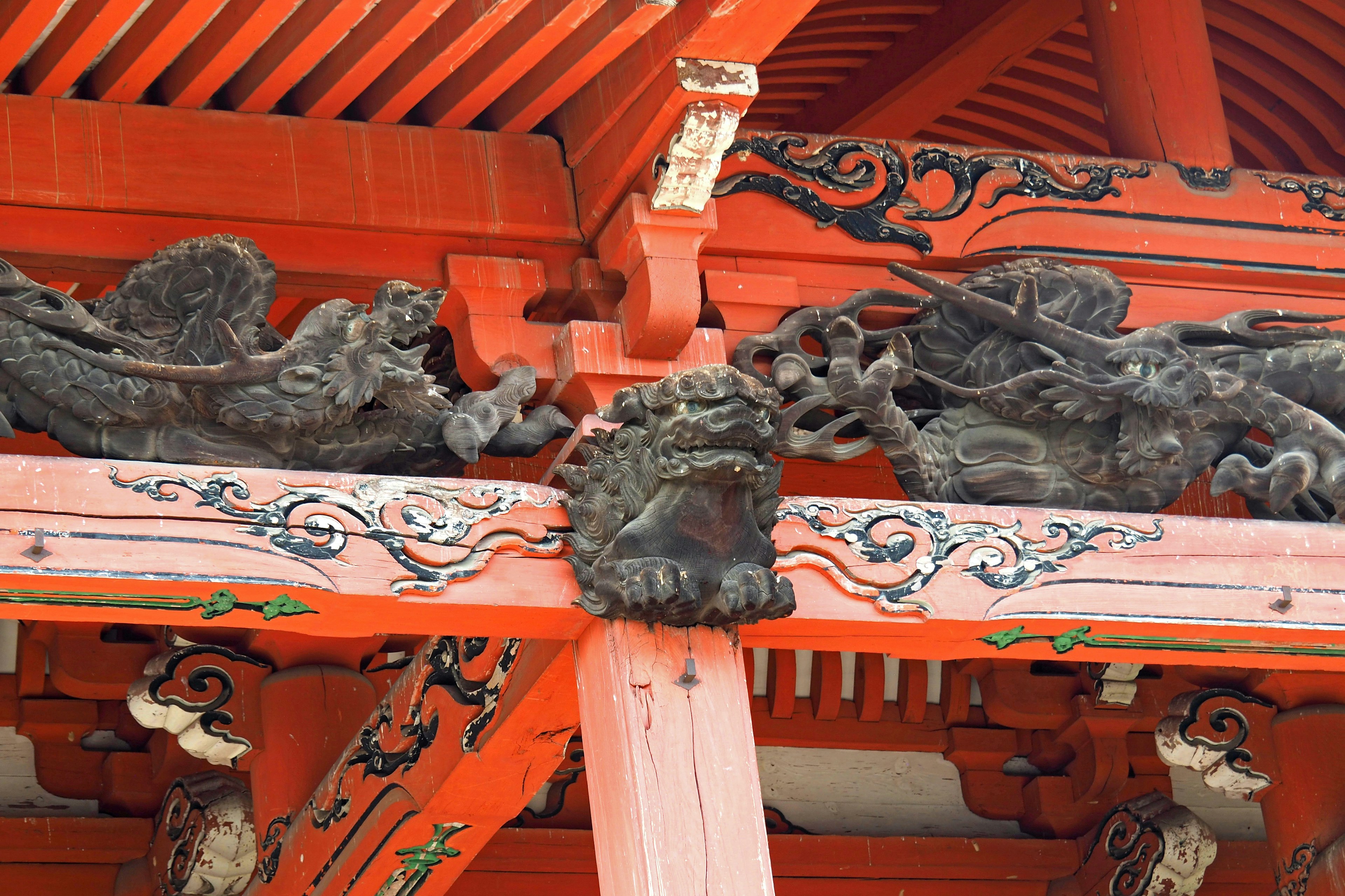 Carved dragon and lion sculptures on the roof of a red temple