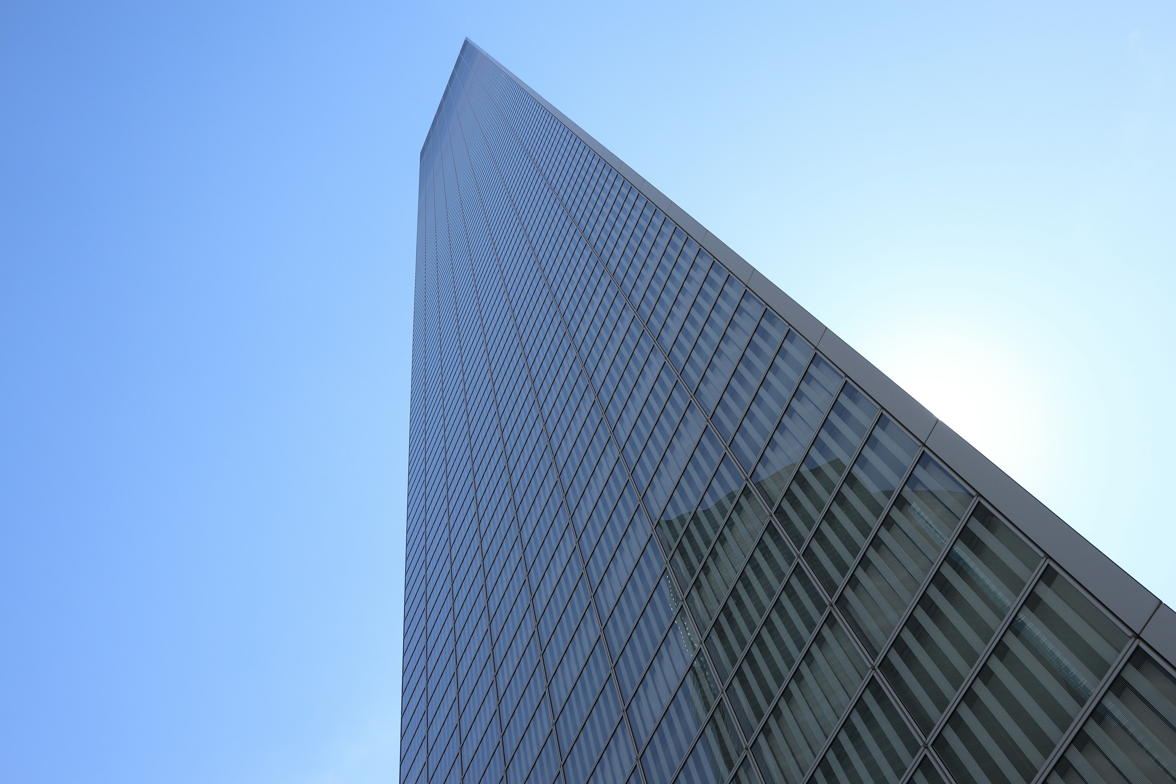 Photograph of a skyscraper from a low angle blue sky and light reflections