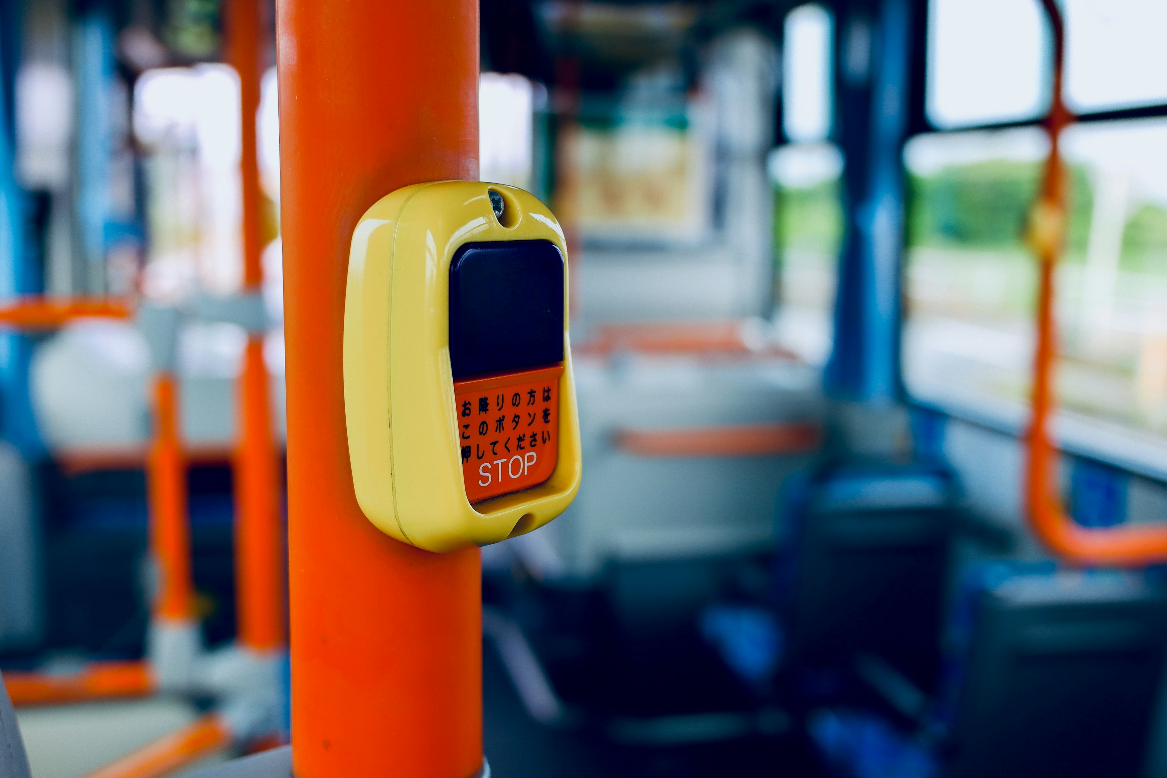 Pulsante di fermata giallo montato su un palo arancione all'interno di un autobus