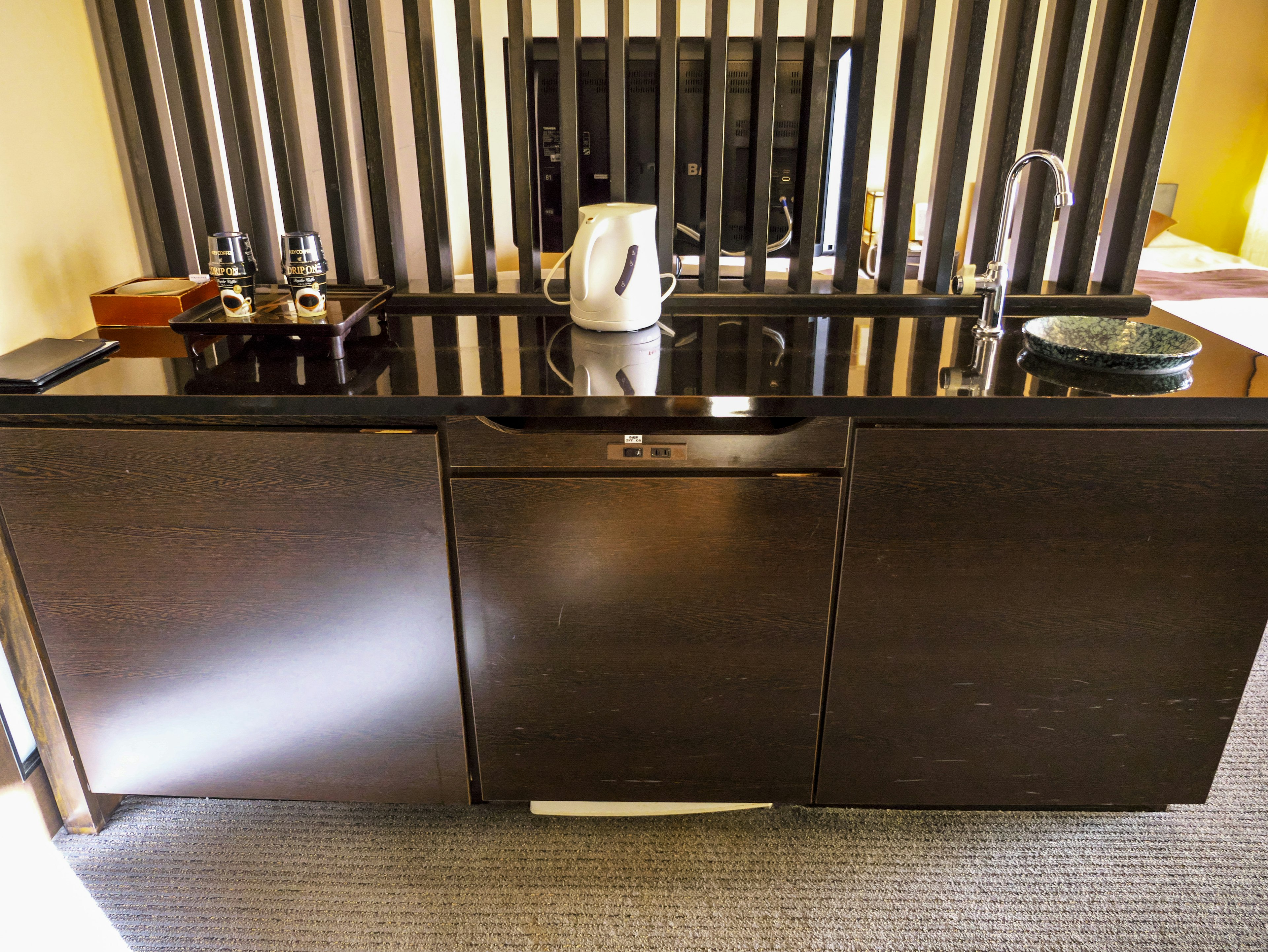 A modern kitchen counter featuring sleek black cabinets and an electric kettle