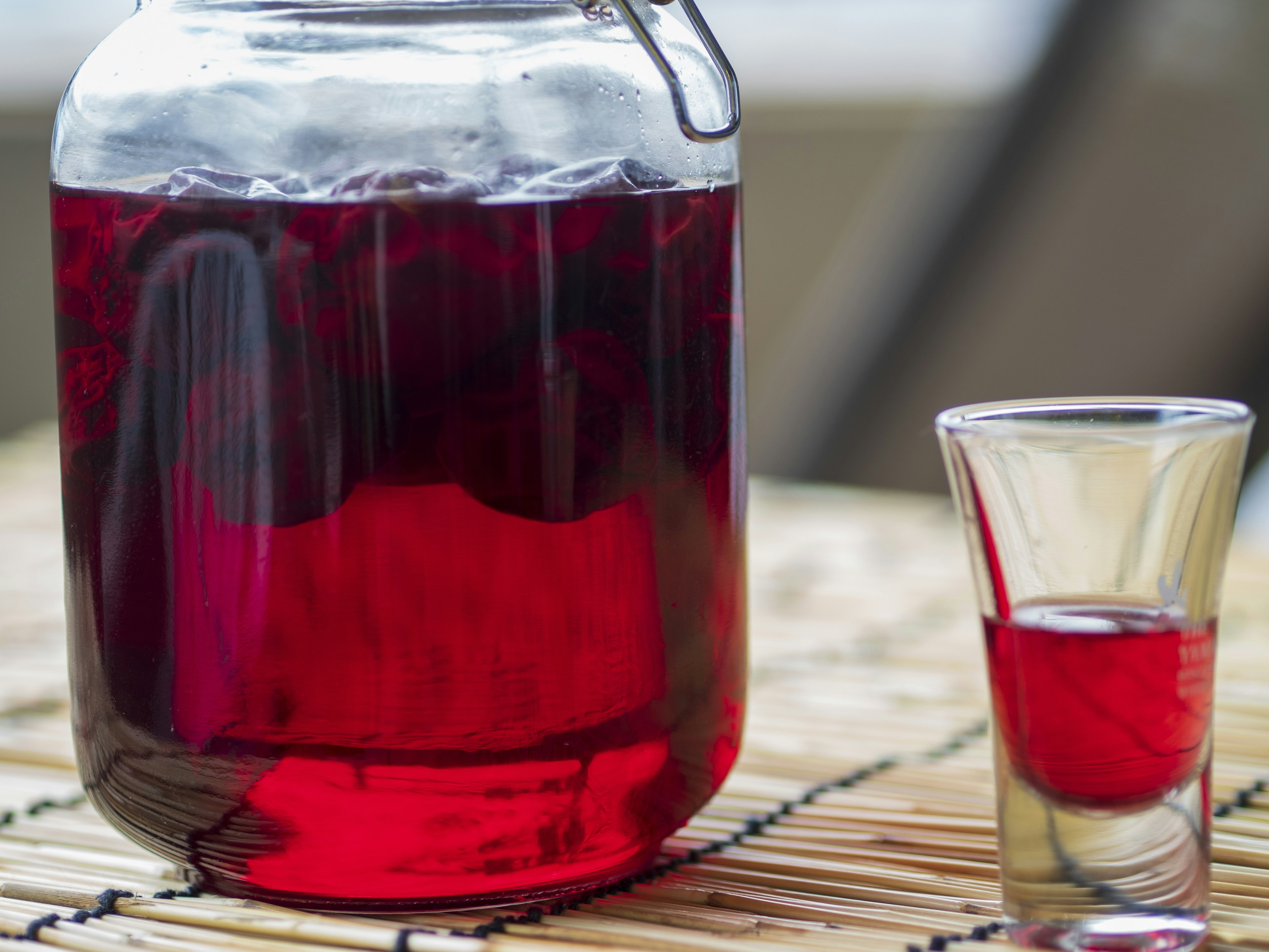 Glasbehälter mit rotem Getränk und einem Schnapsglas