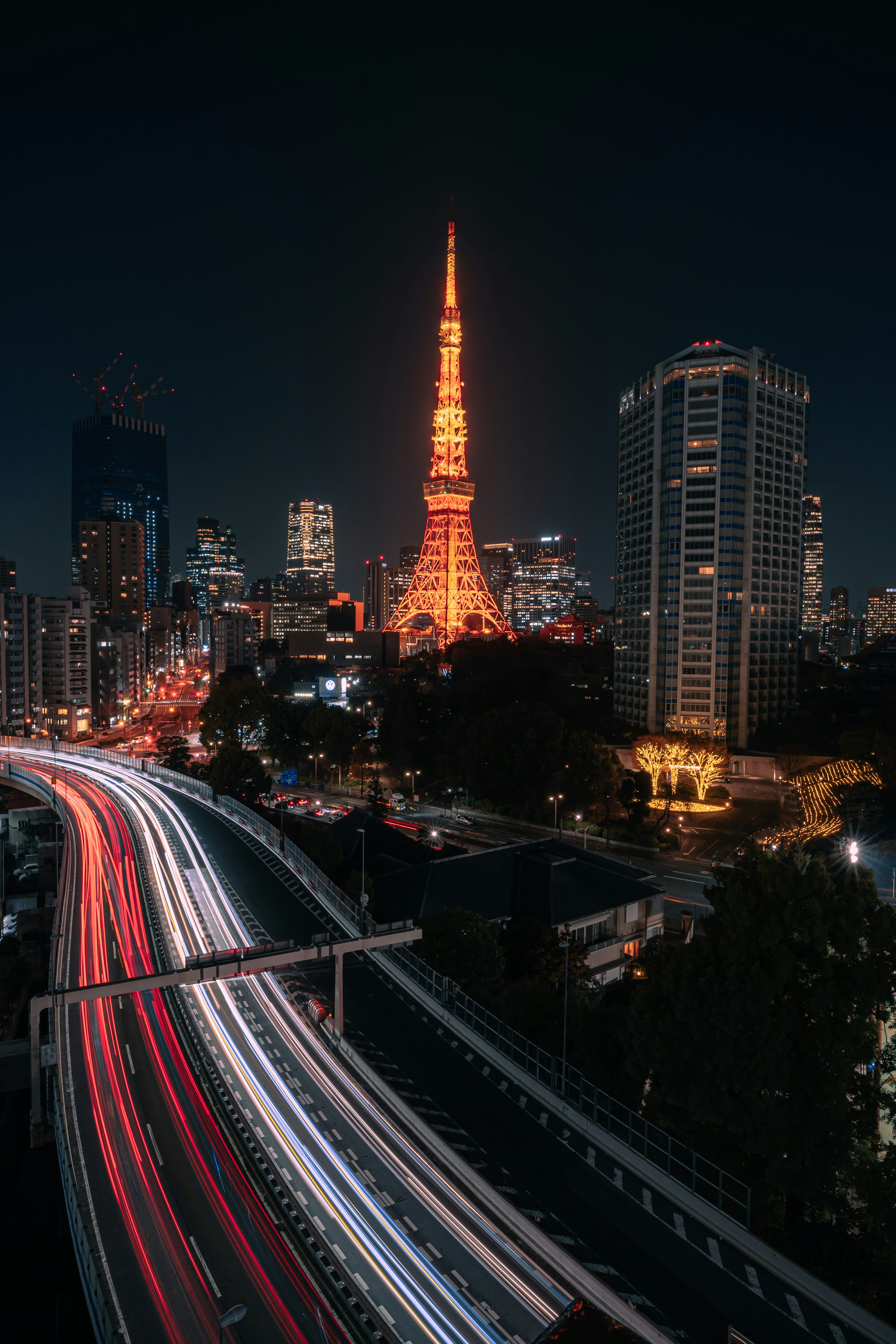 Tokyo Tower illuminata di notte con skyline cittadino e traiettorie di luce delle auto