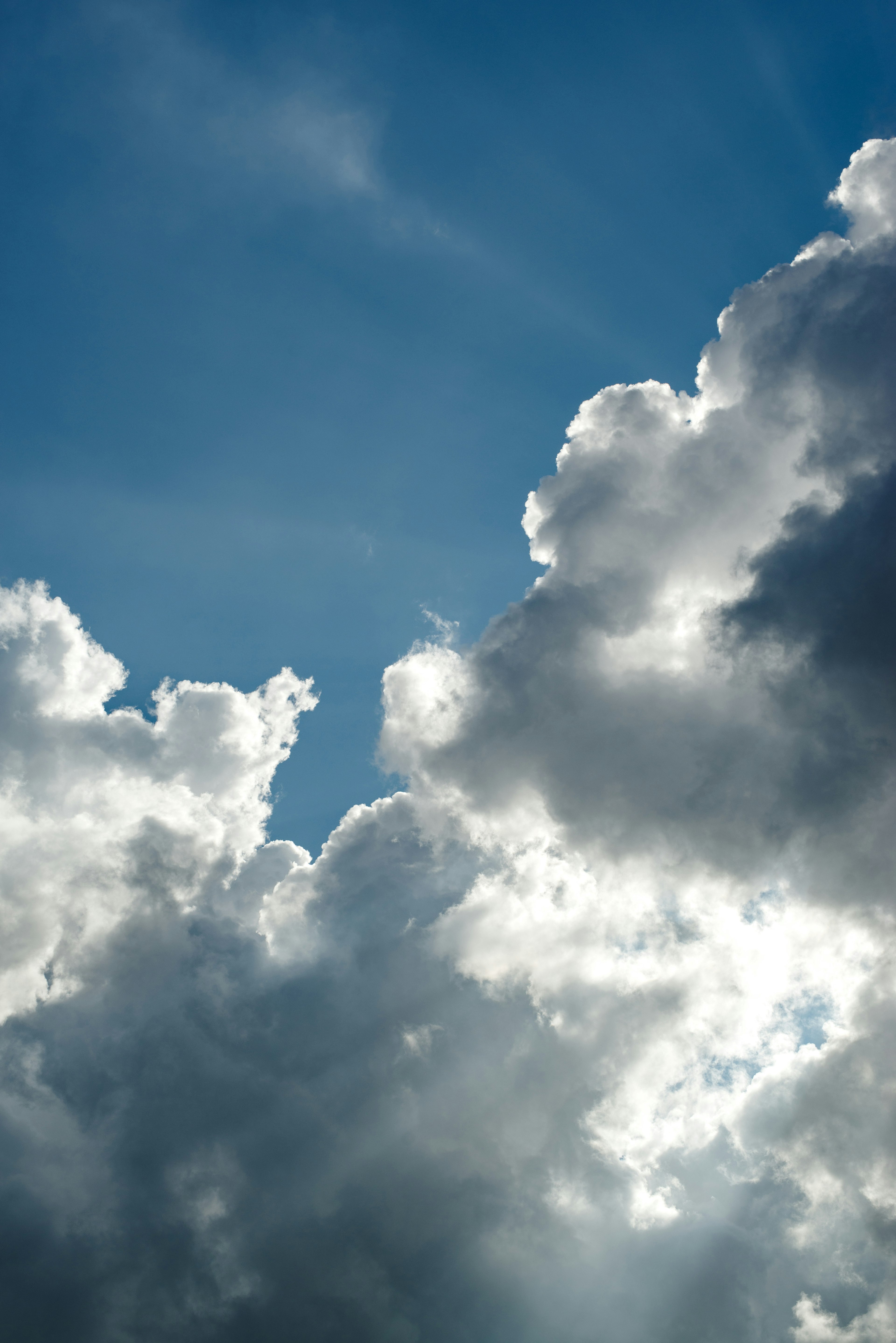 Awan putih yang diterangi sinar matahari di latar belakang langit biru