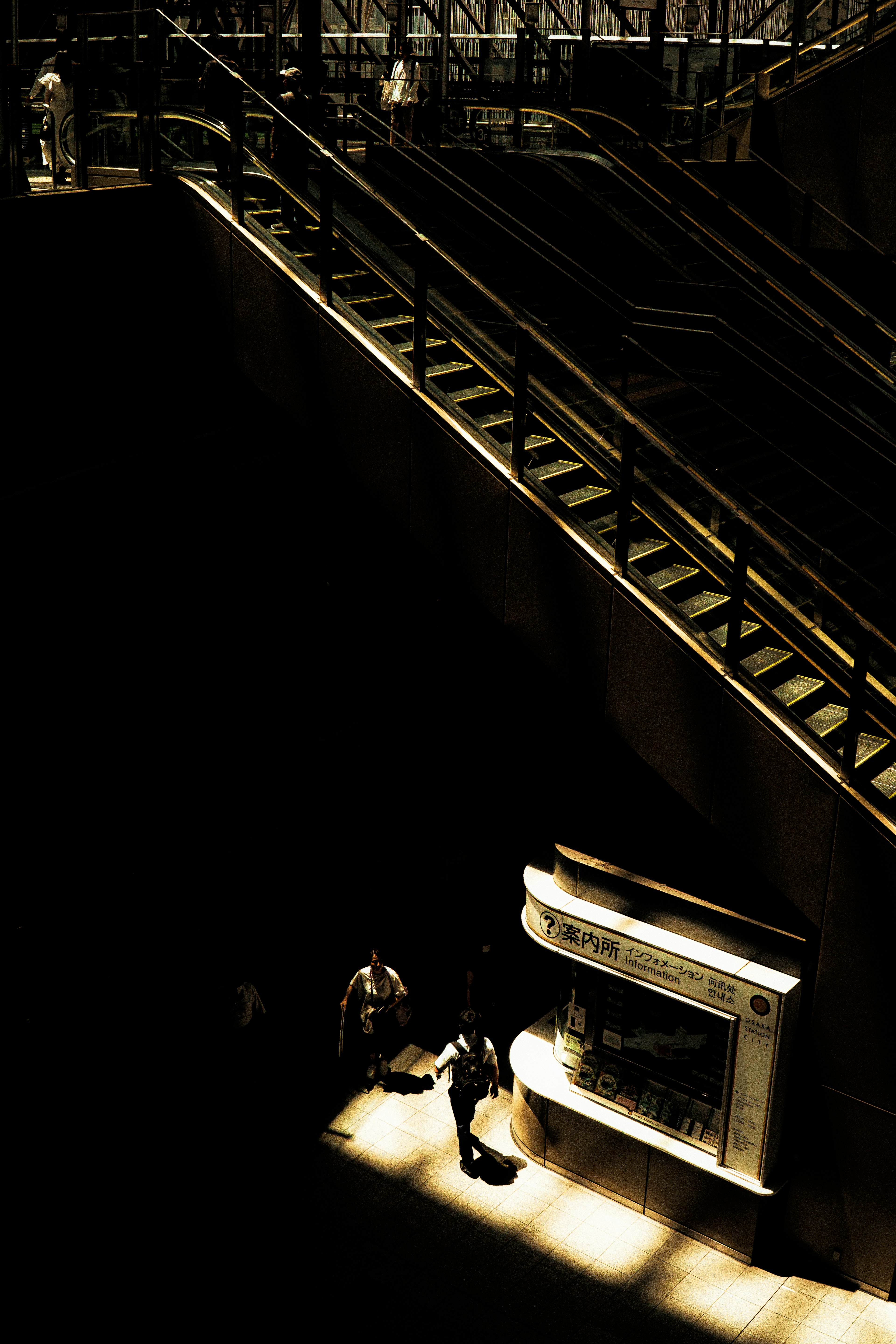 Contraste de luz con escalera brillante y dos personas en un espacio oscuro