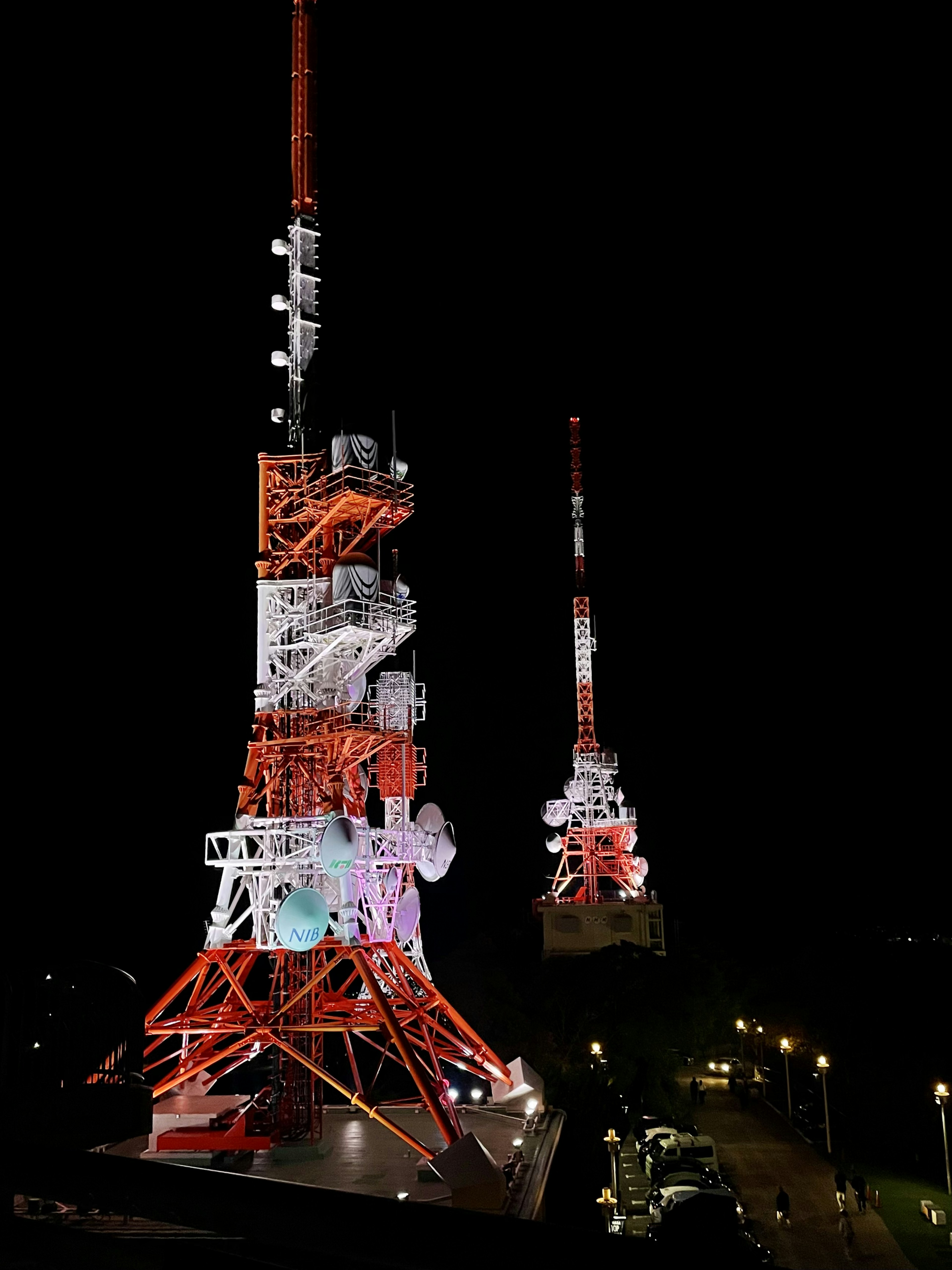 Menara Tokyo dan menara antena terdekat yang diterangi di malam hari