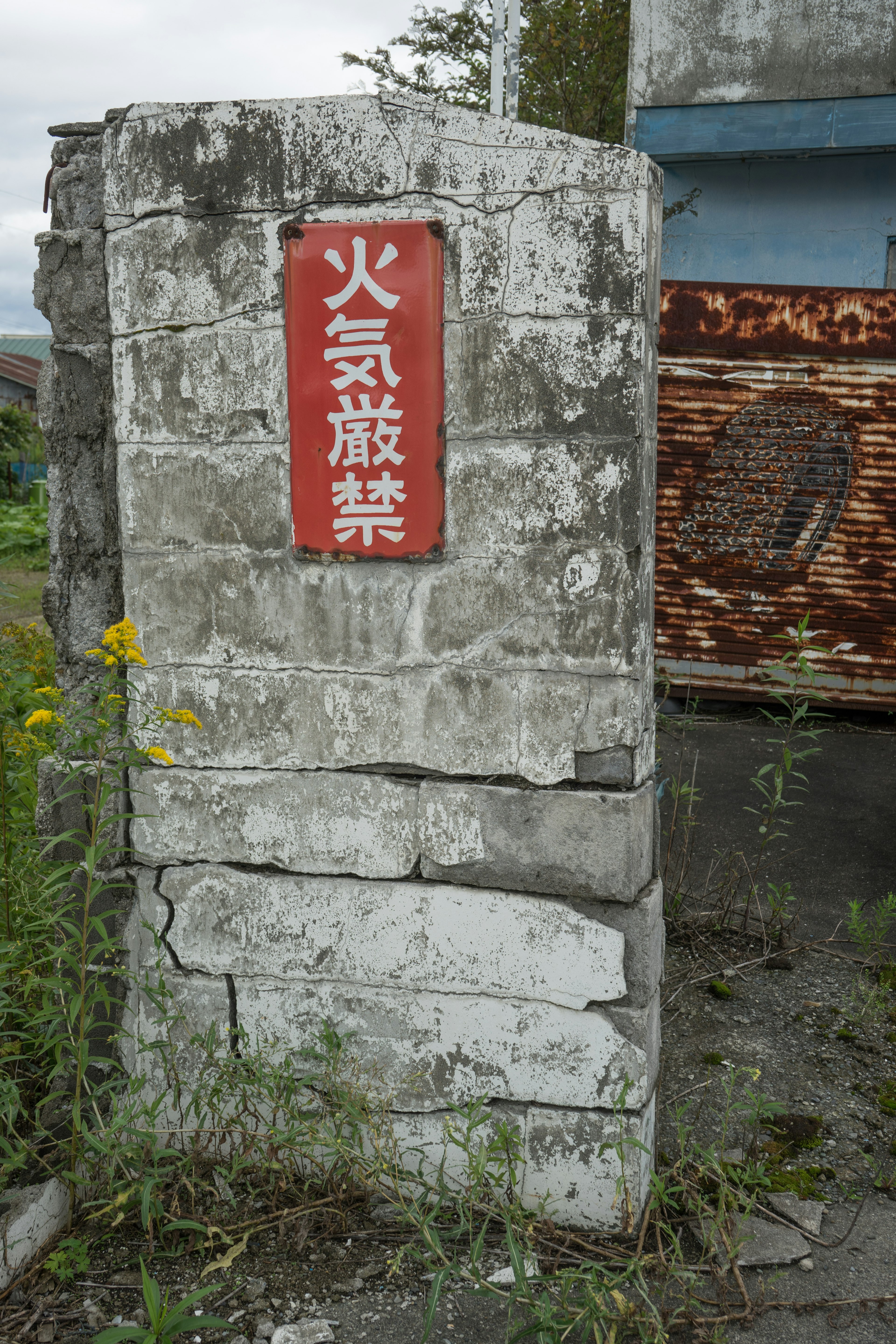 Stone marker with a red sign surrounded by grass