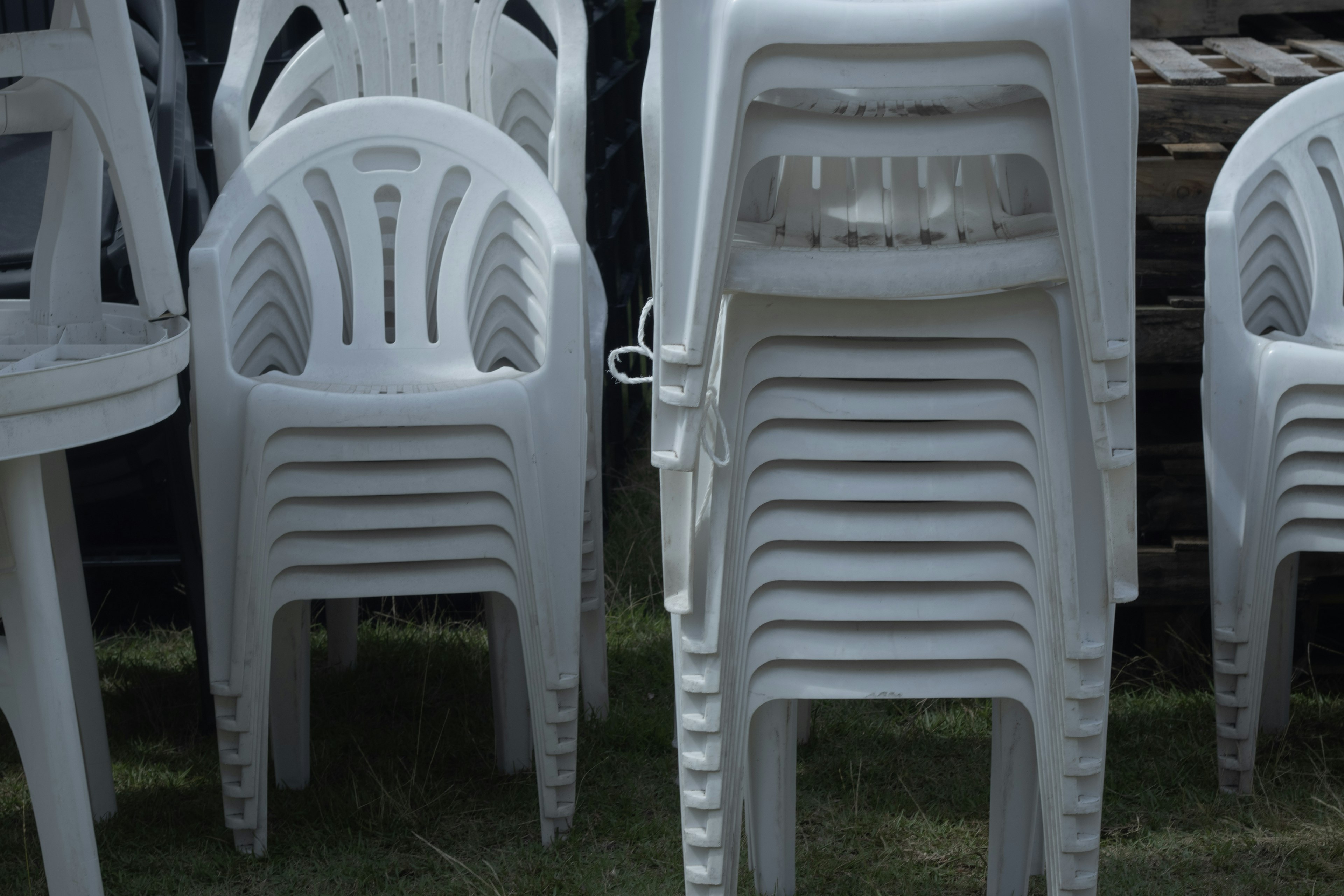 Stacked white plastic chairs in a garden setting