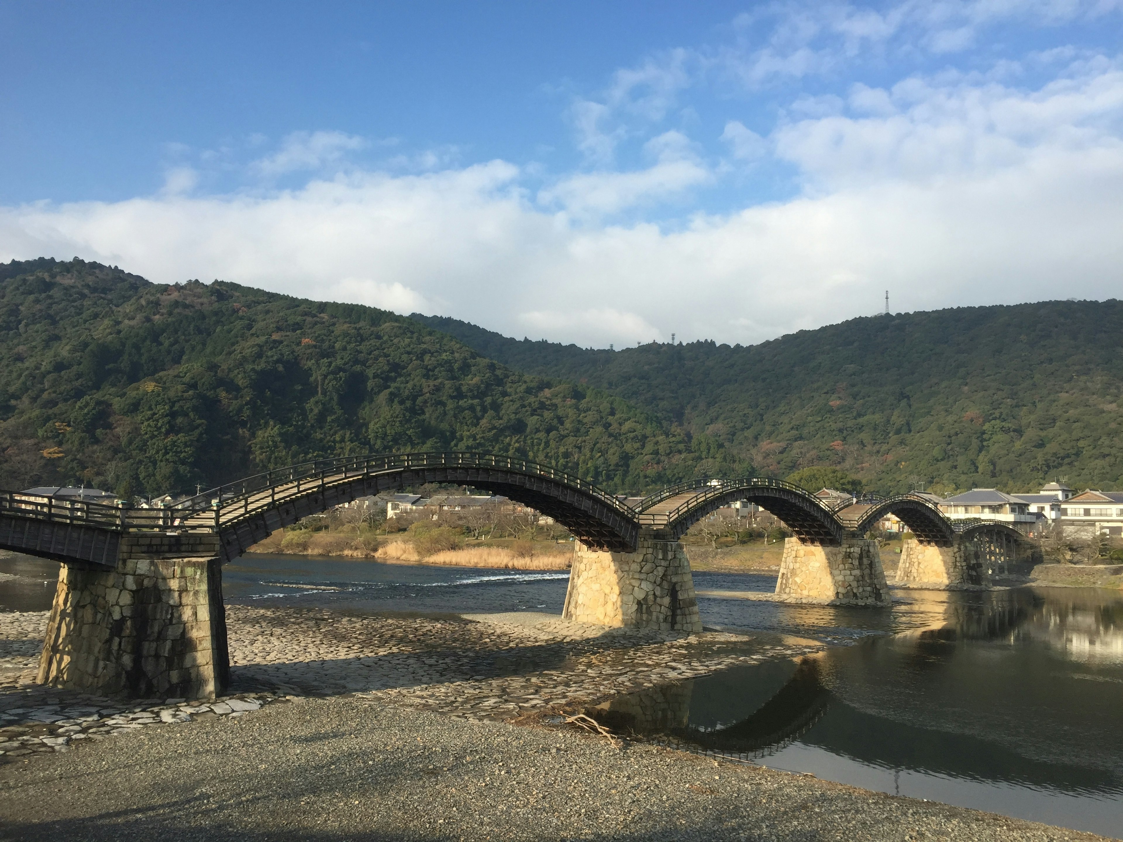 Un bellissimo ponte ad arco attraversa un fiume circondato da montagne verdi