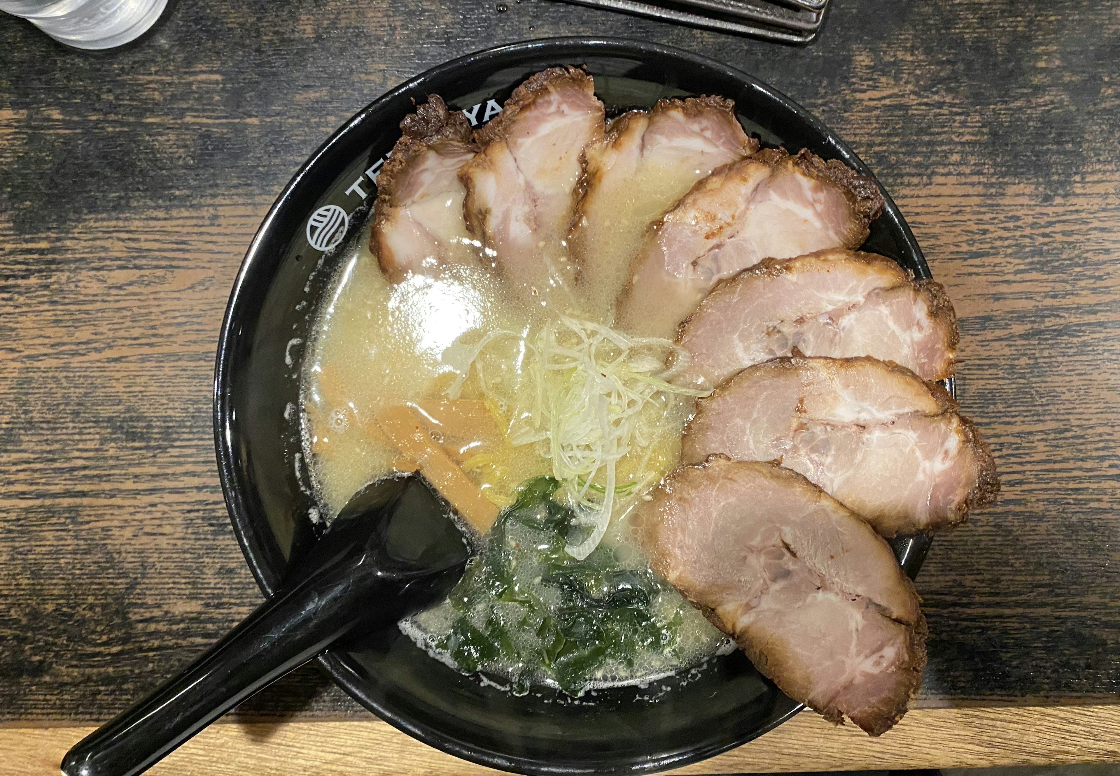 Eine Schüssel Ramen mit Scheiben von Chashu-Schweinefleisch in Brühe, garniert mit Frühlingszwiebeln und Algen