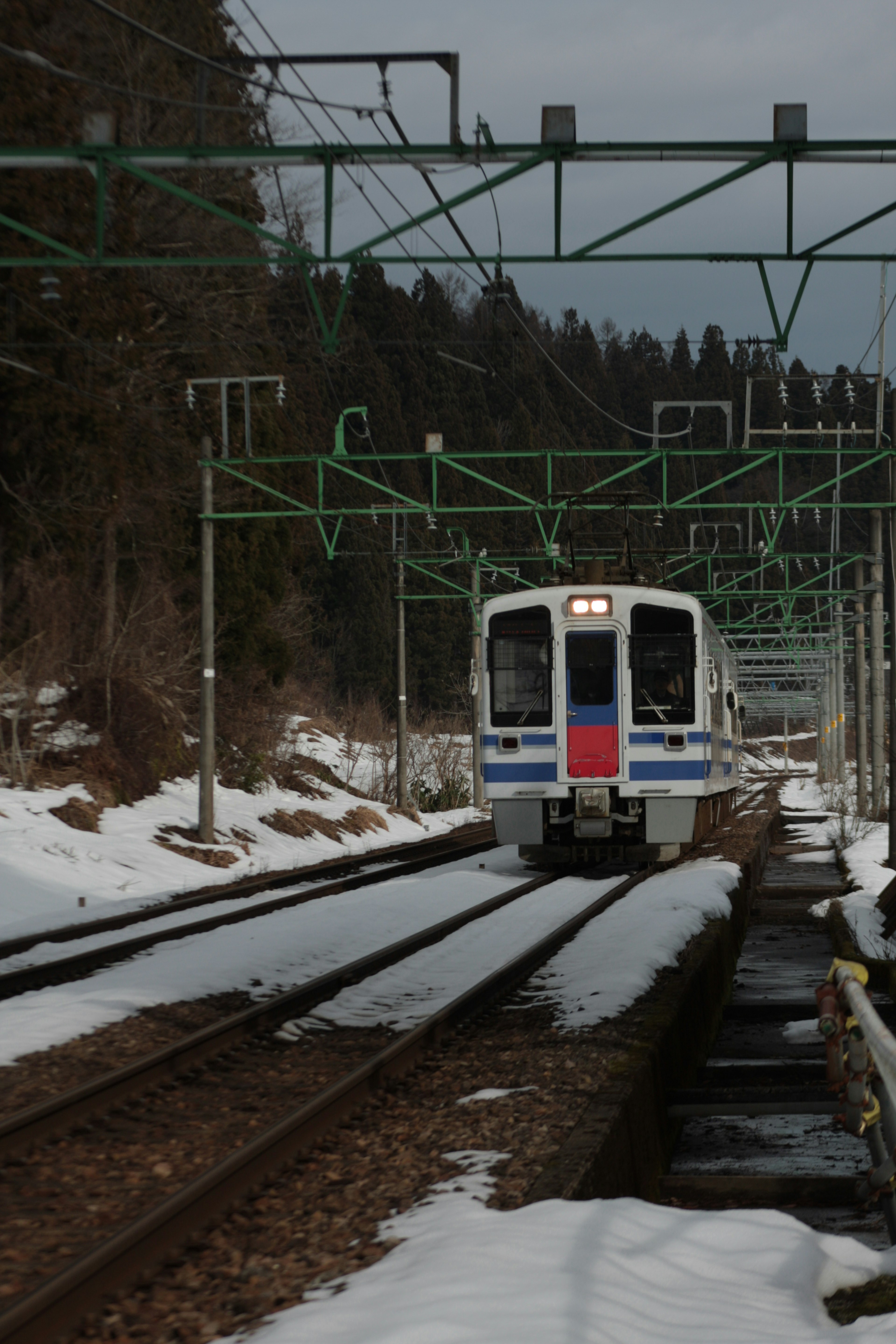 Train on snowy tracks with overhead electric lines