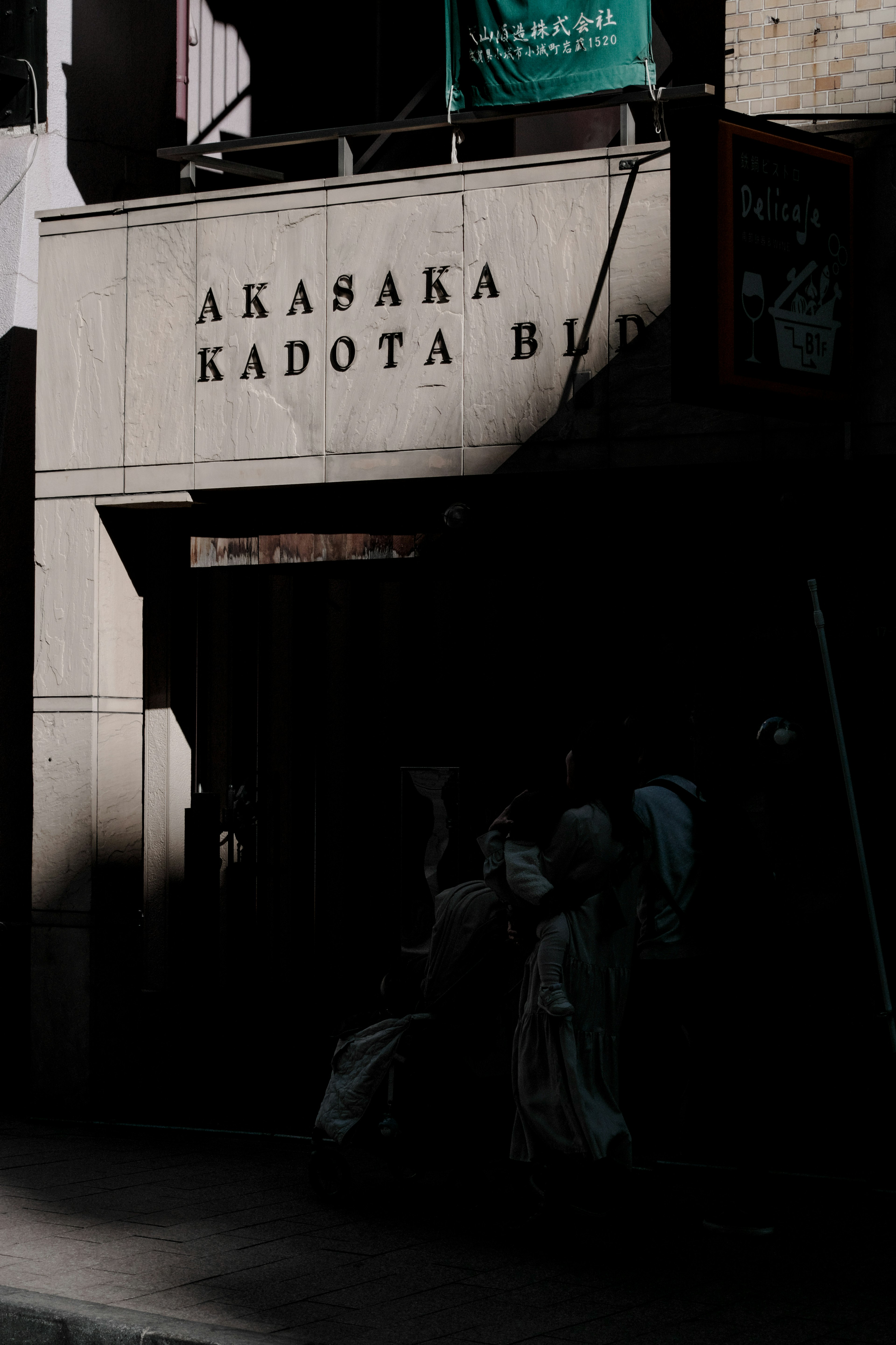 Schild des Akasaka Kadota Gebäudes teilweise im Schatten