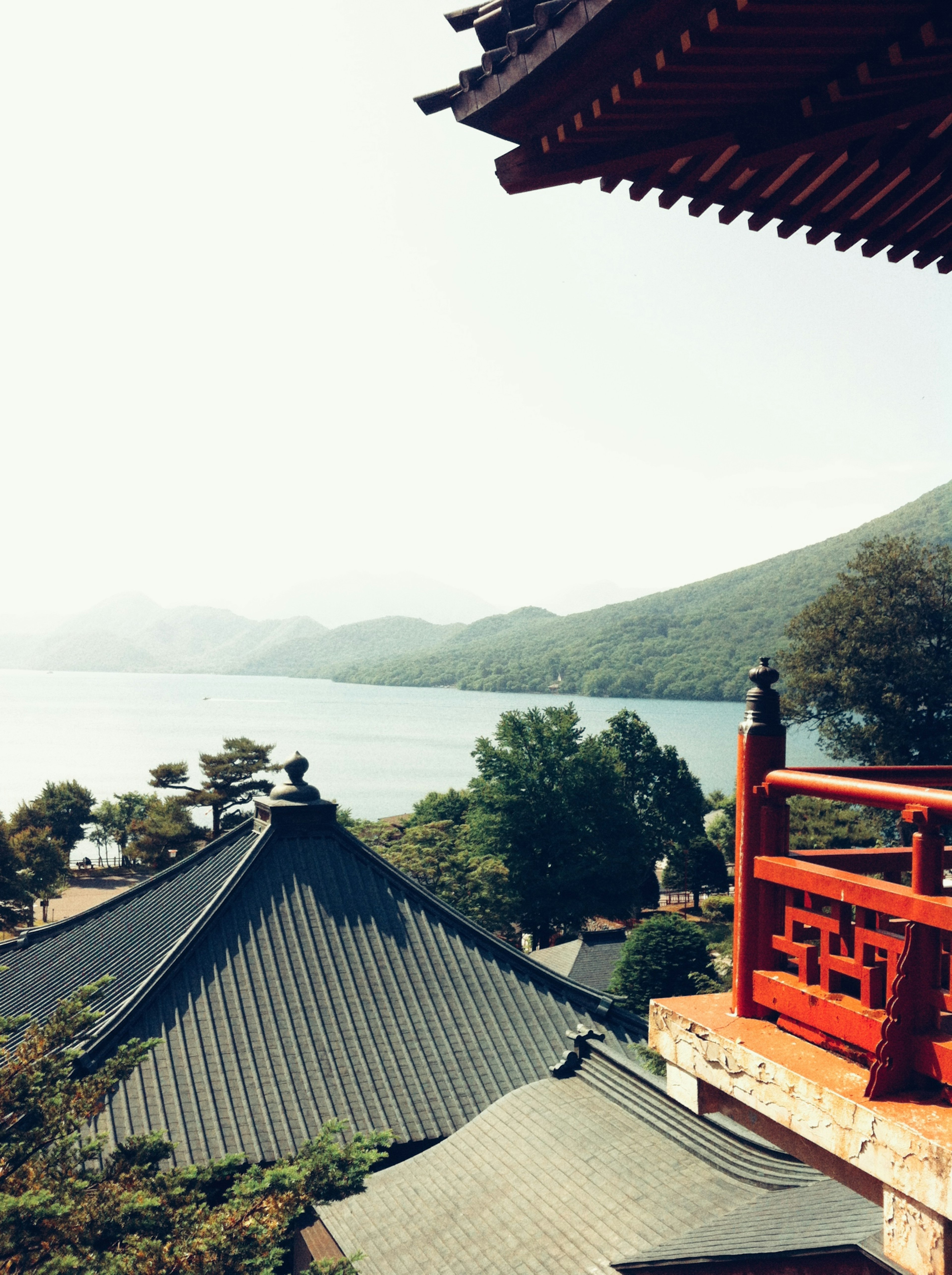 傳統屋頂俯瞰寧靜湖泊和背景山脈