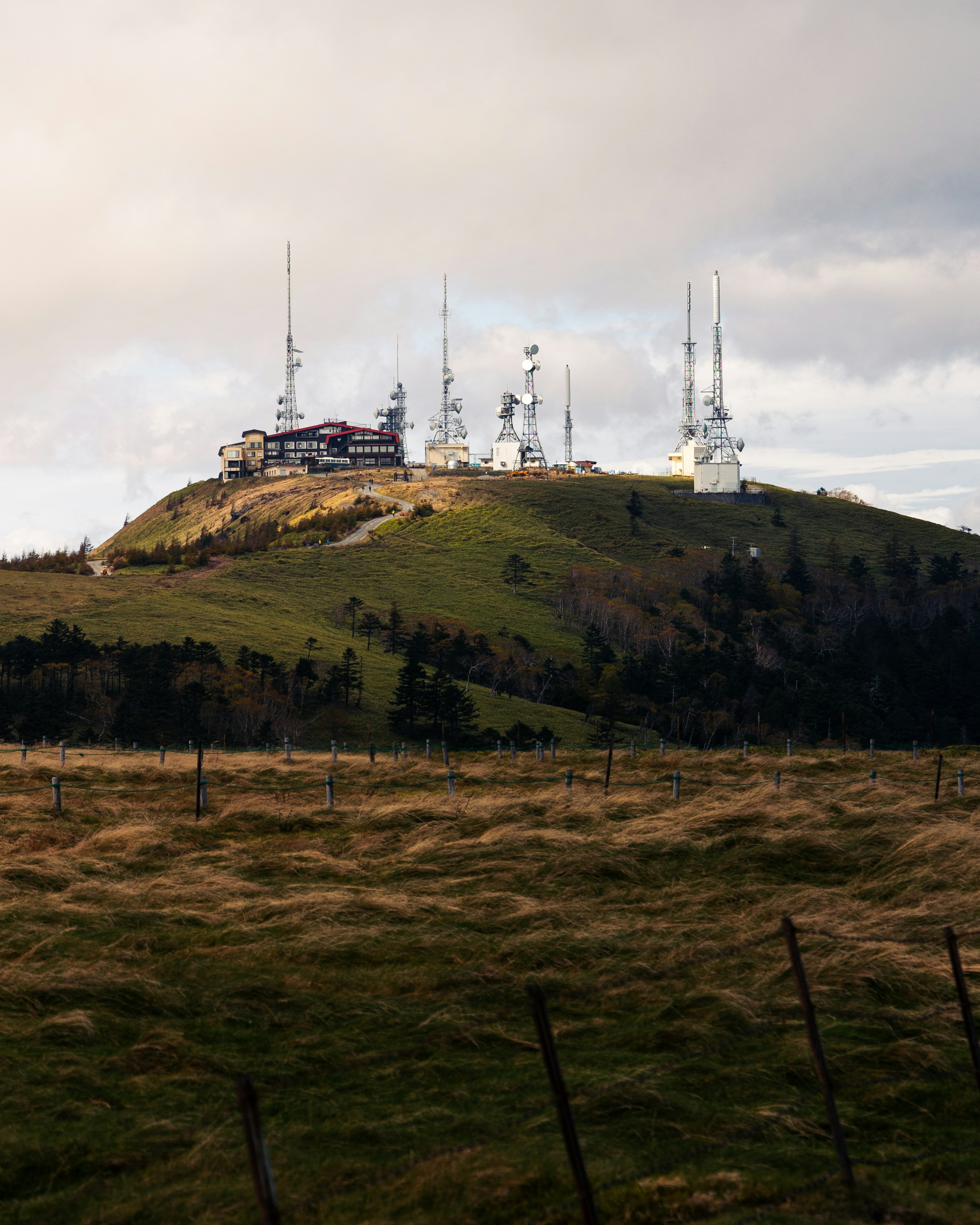 Communication towers on a hill with a cloudy sky