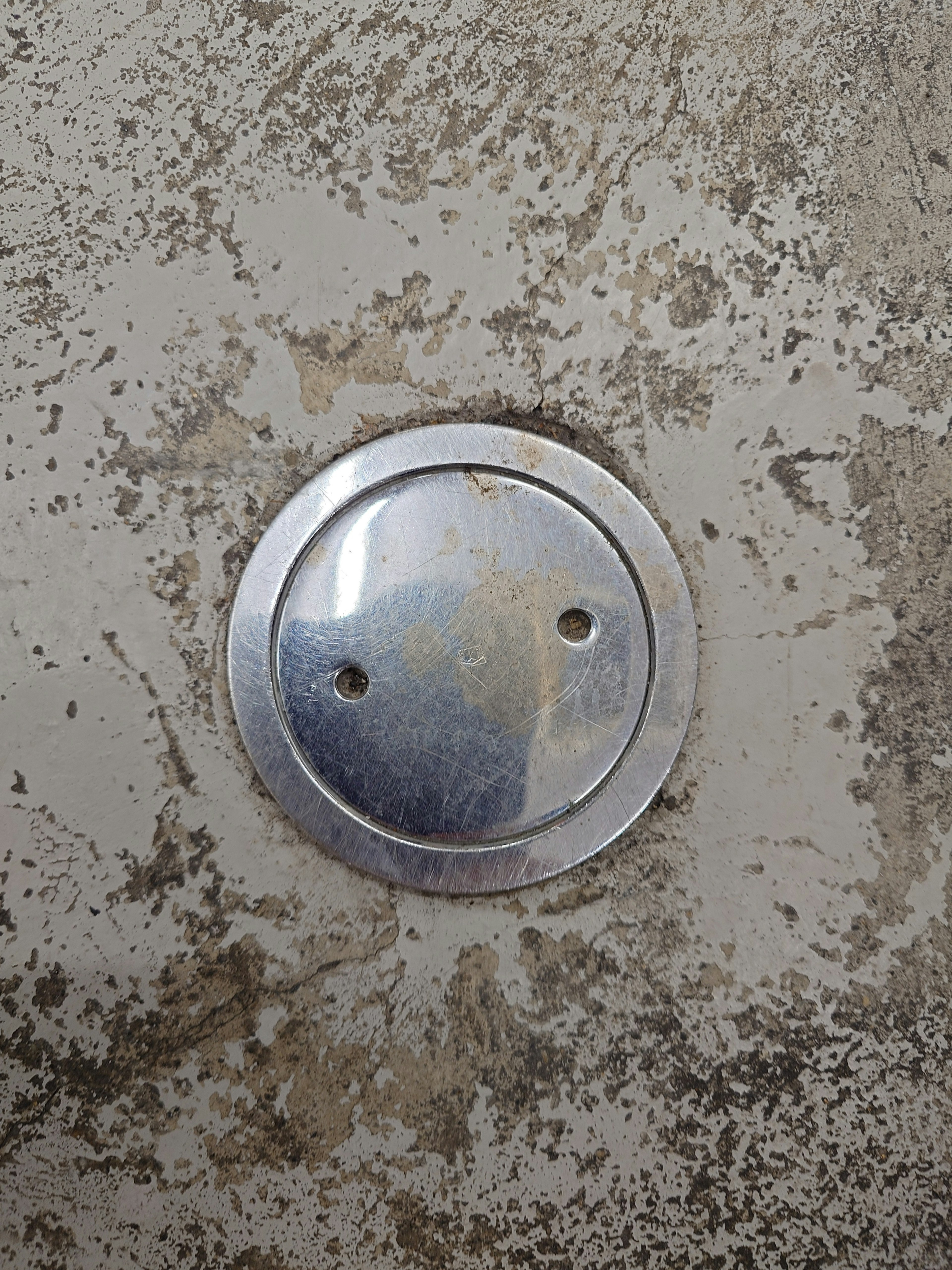 Image of a metallic circular plate with two holes on a textured surface