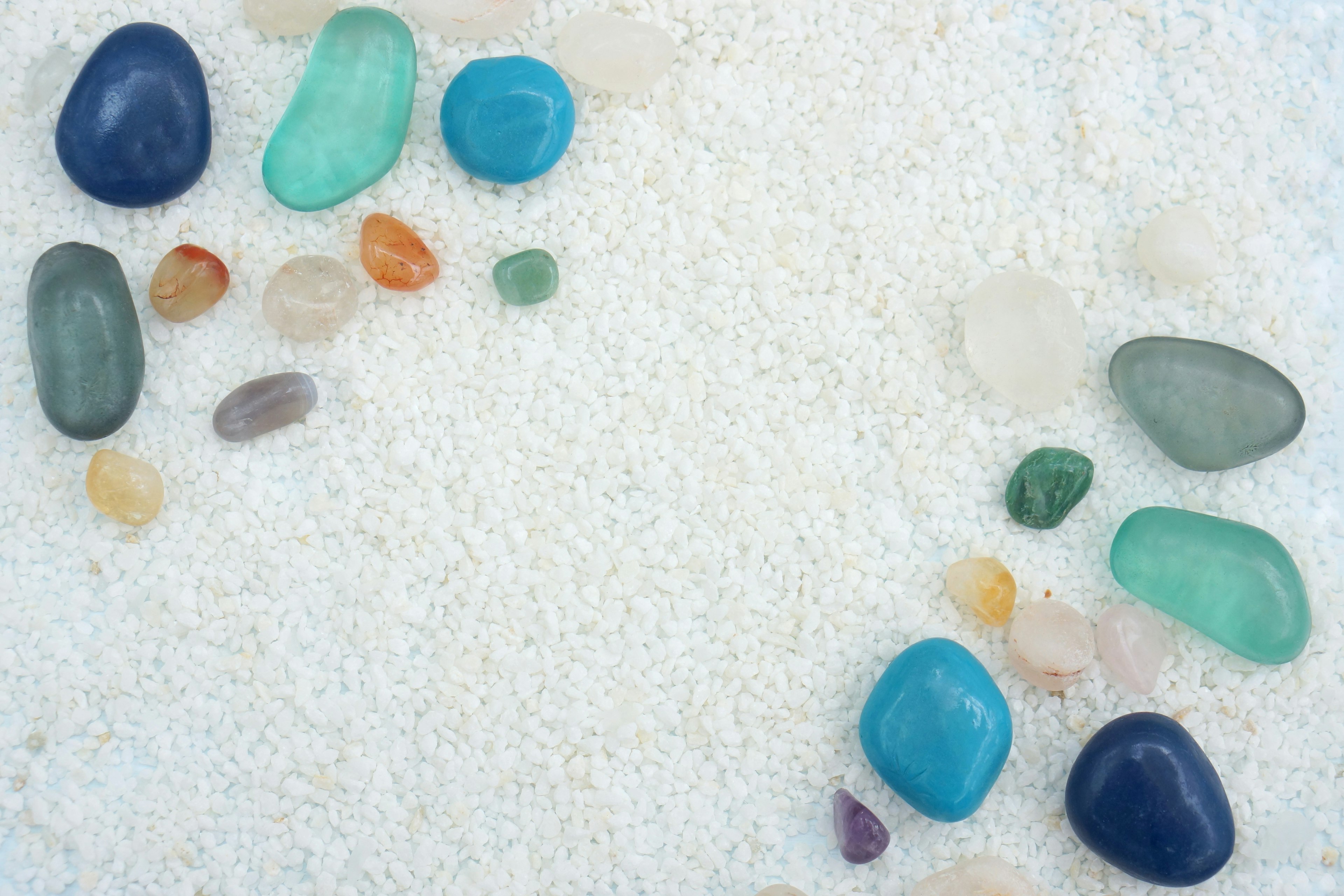 Des pierres colorées éparpillées sur du sable blanc