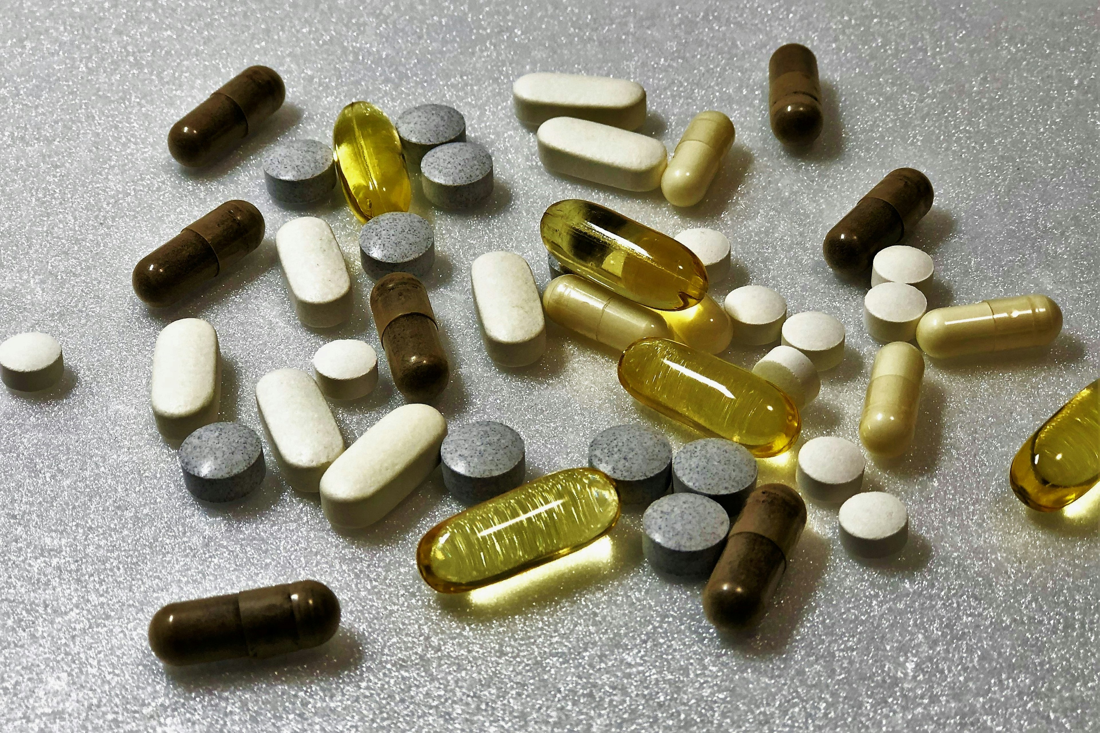 Una varietà di capsule e compresse colorate sparse su una superficie