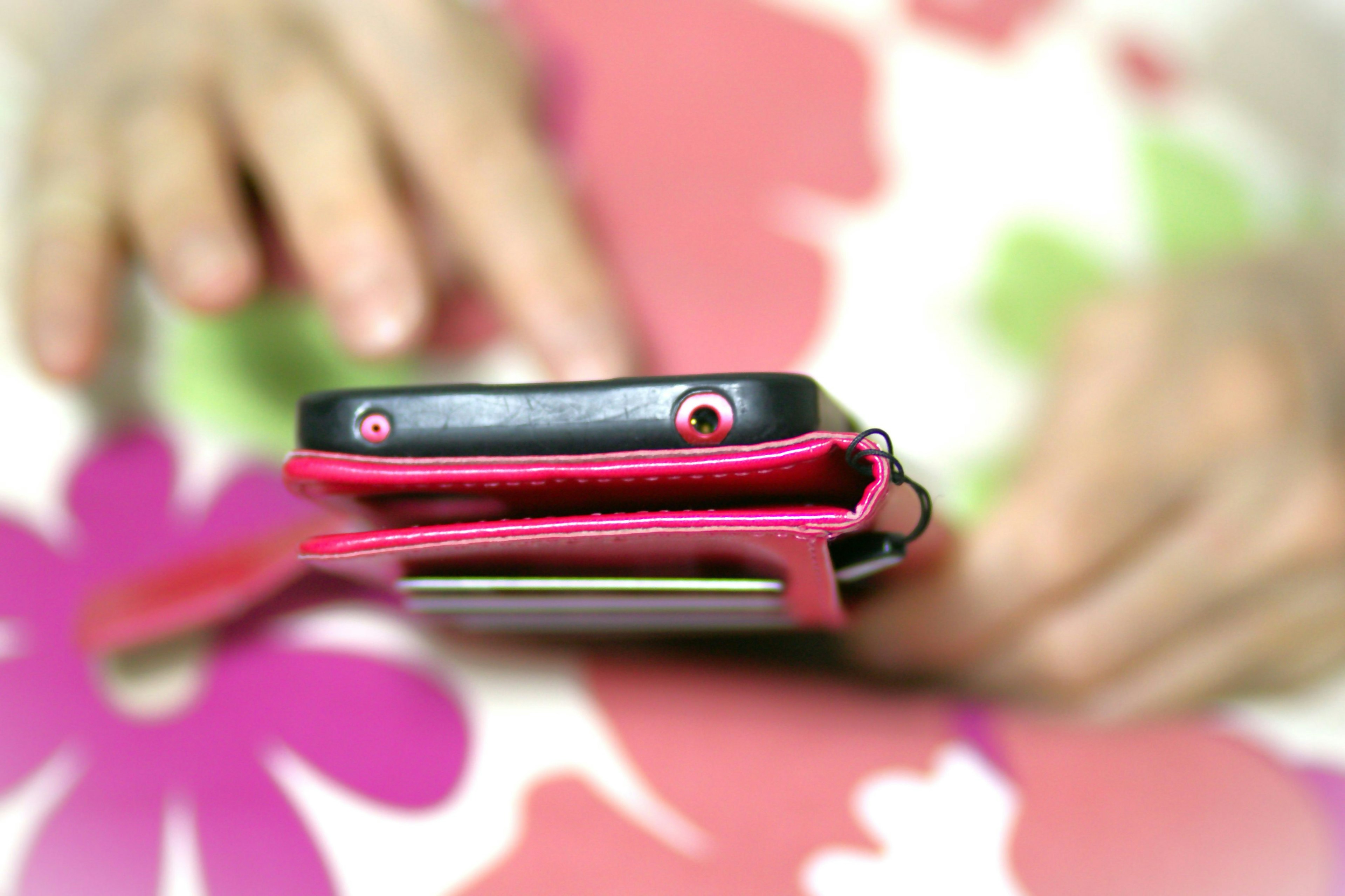 Smartphone dans une housse rose sur une nappe à fleurs