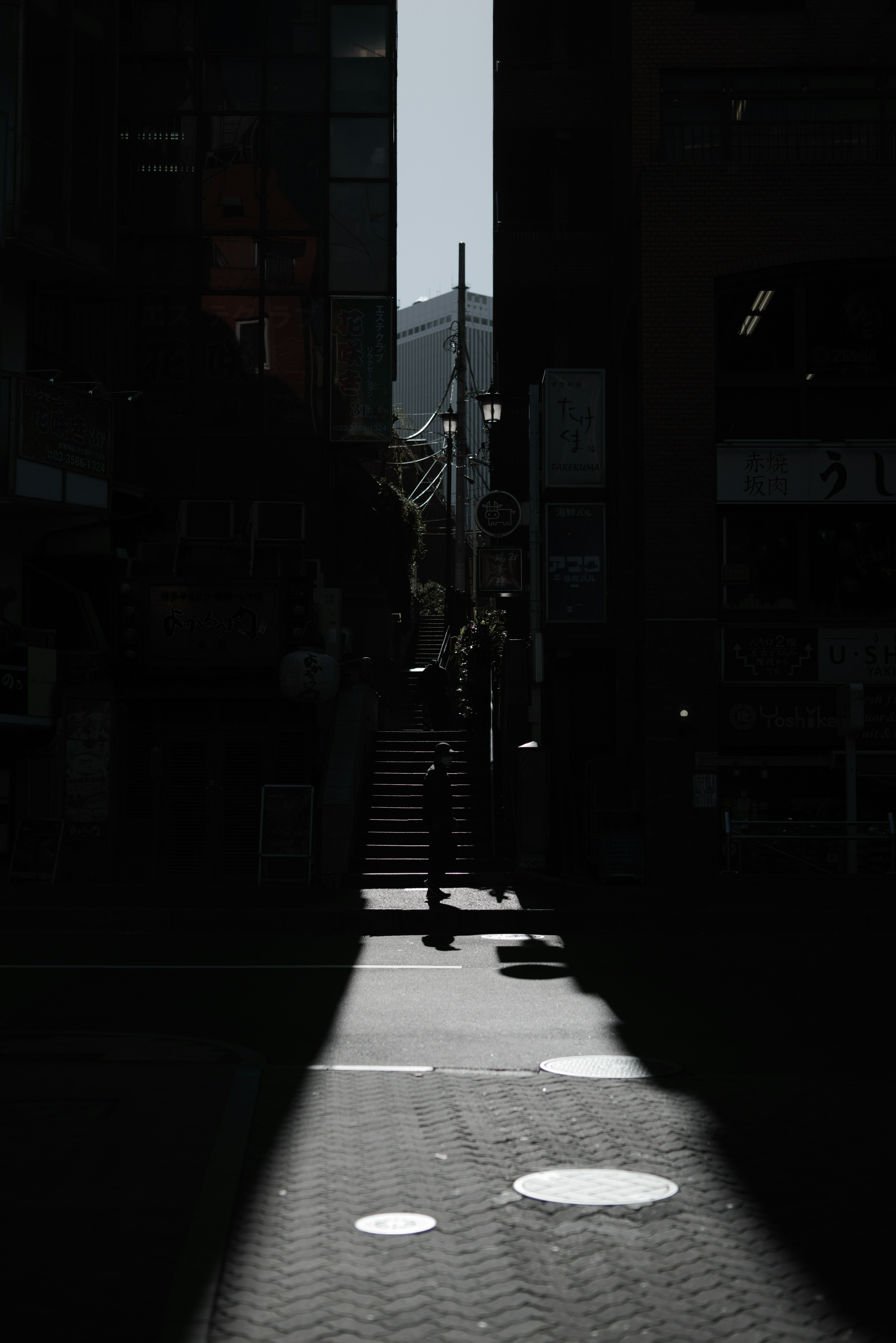 暗い通りの中に明るい階段が見える街の風景