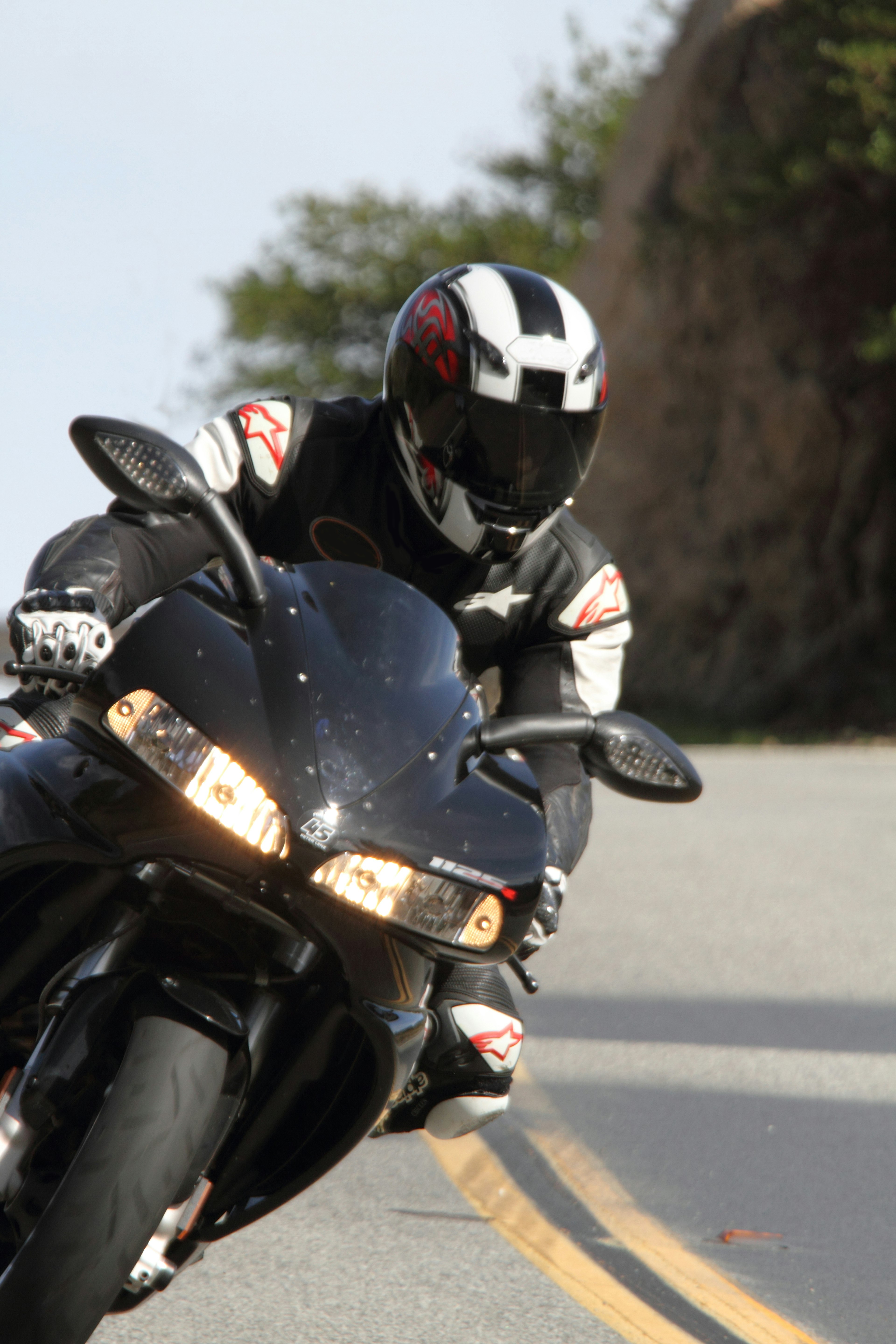 A rider on a black motorcycle navigating a curve on a winding road