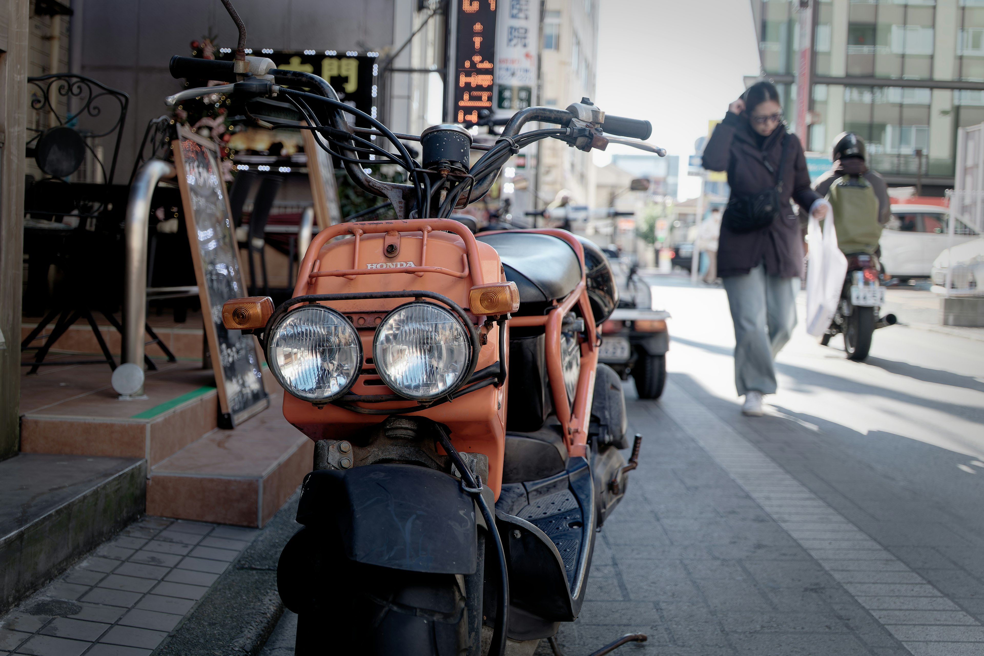 Moto arancione parcheggiata in strada con pedoni nelle vicinanze