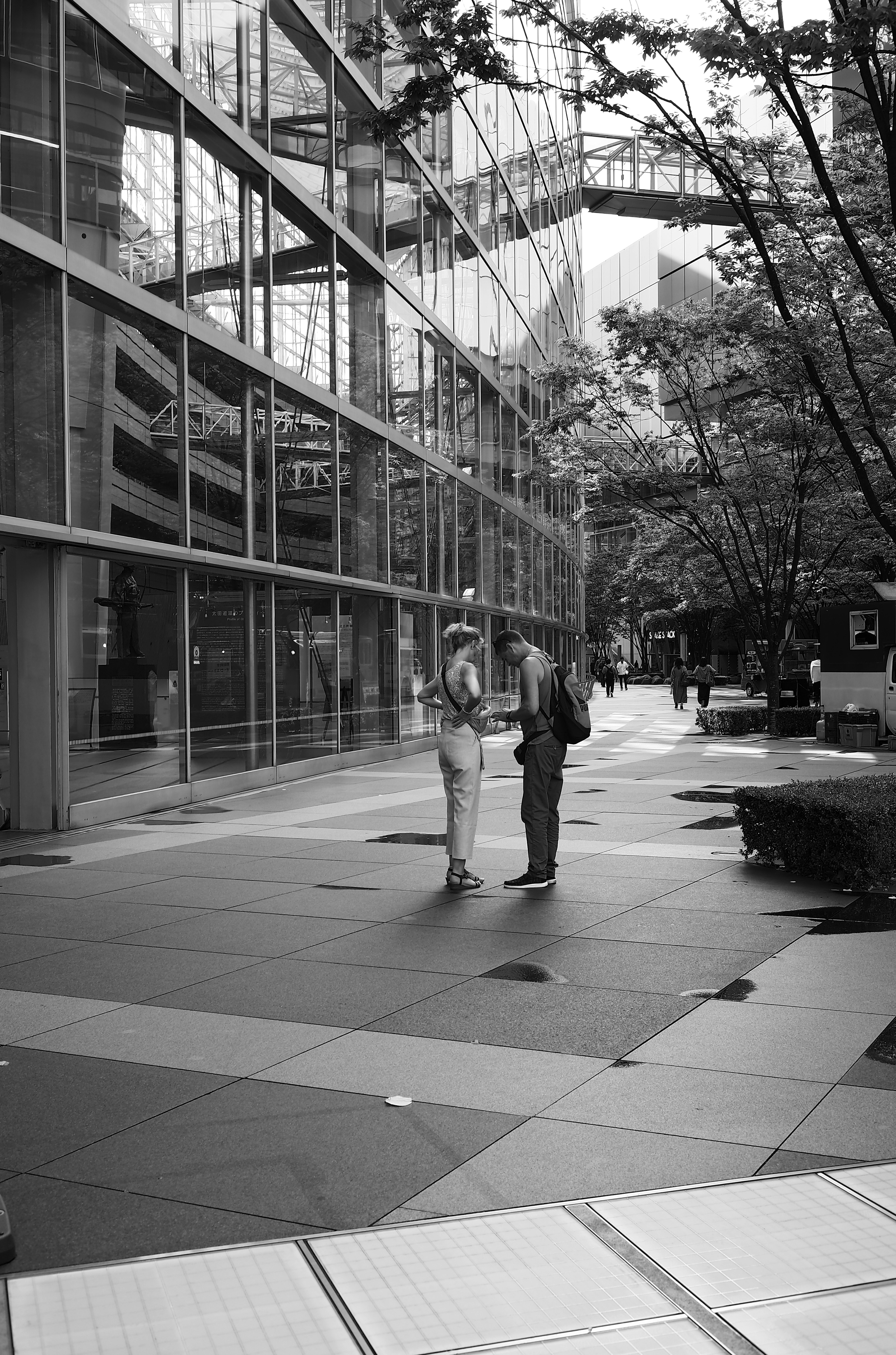 Dos personas conversando frente a un edificio moderno en blanco y negro