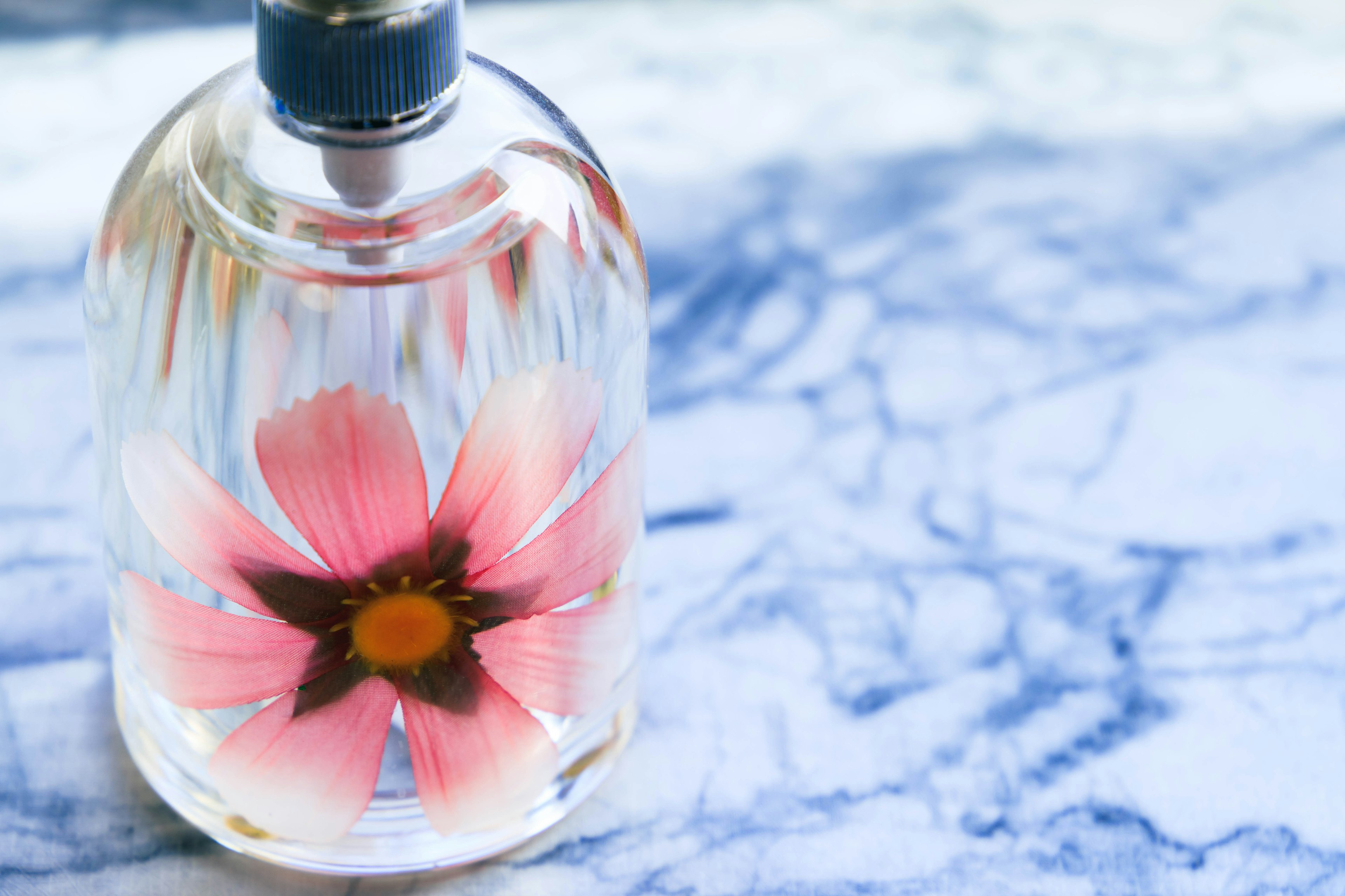 Botella de perfume transparente con una flor rosa dentro