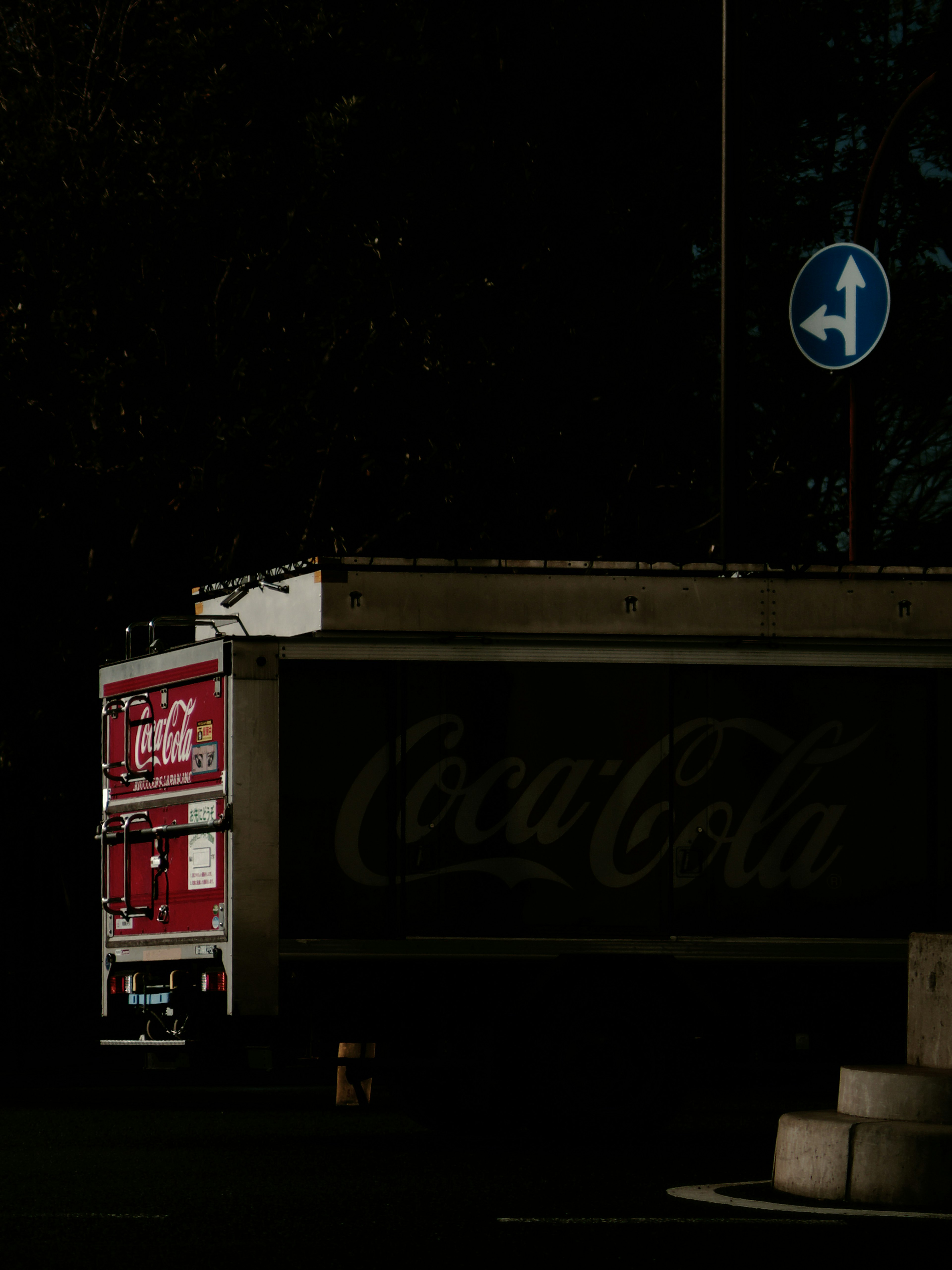 Camion rouge Coca-Cola sur un fond sombre avec un panneau de circulation