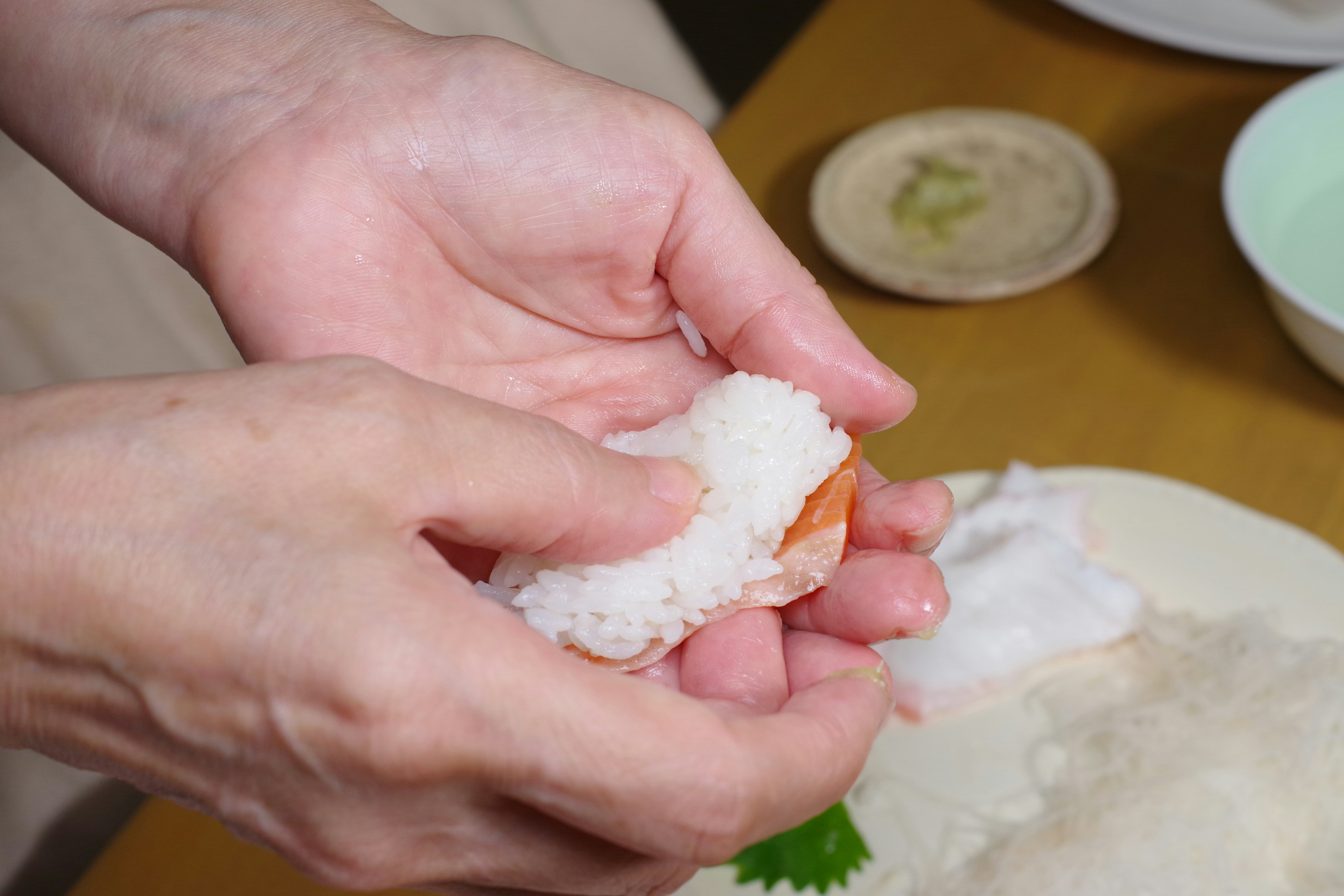 Mani che modellano il riso sushi con frutti di mare