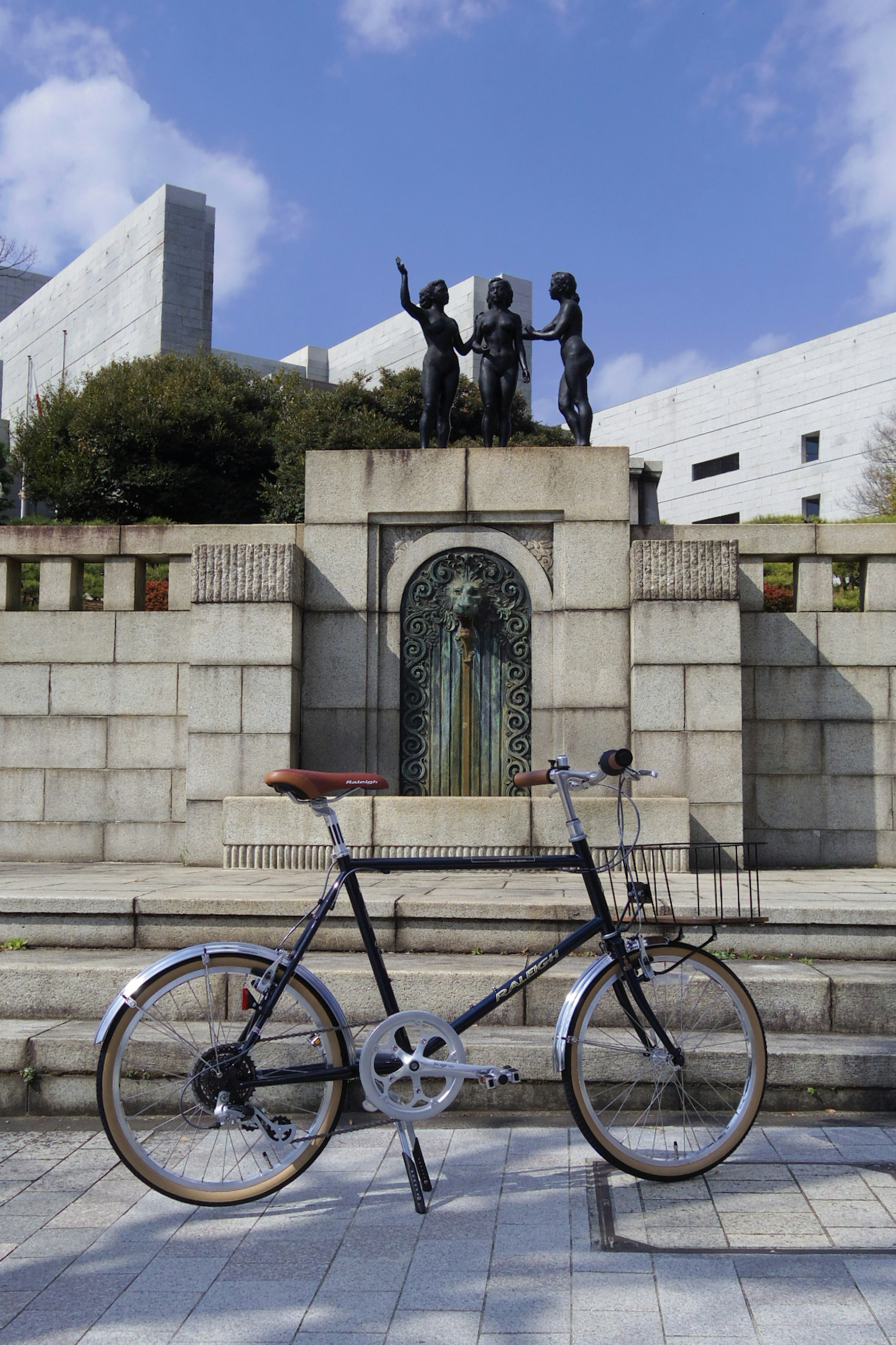 A black bicycle in front of a stone fountain with sculptures