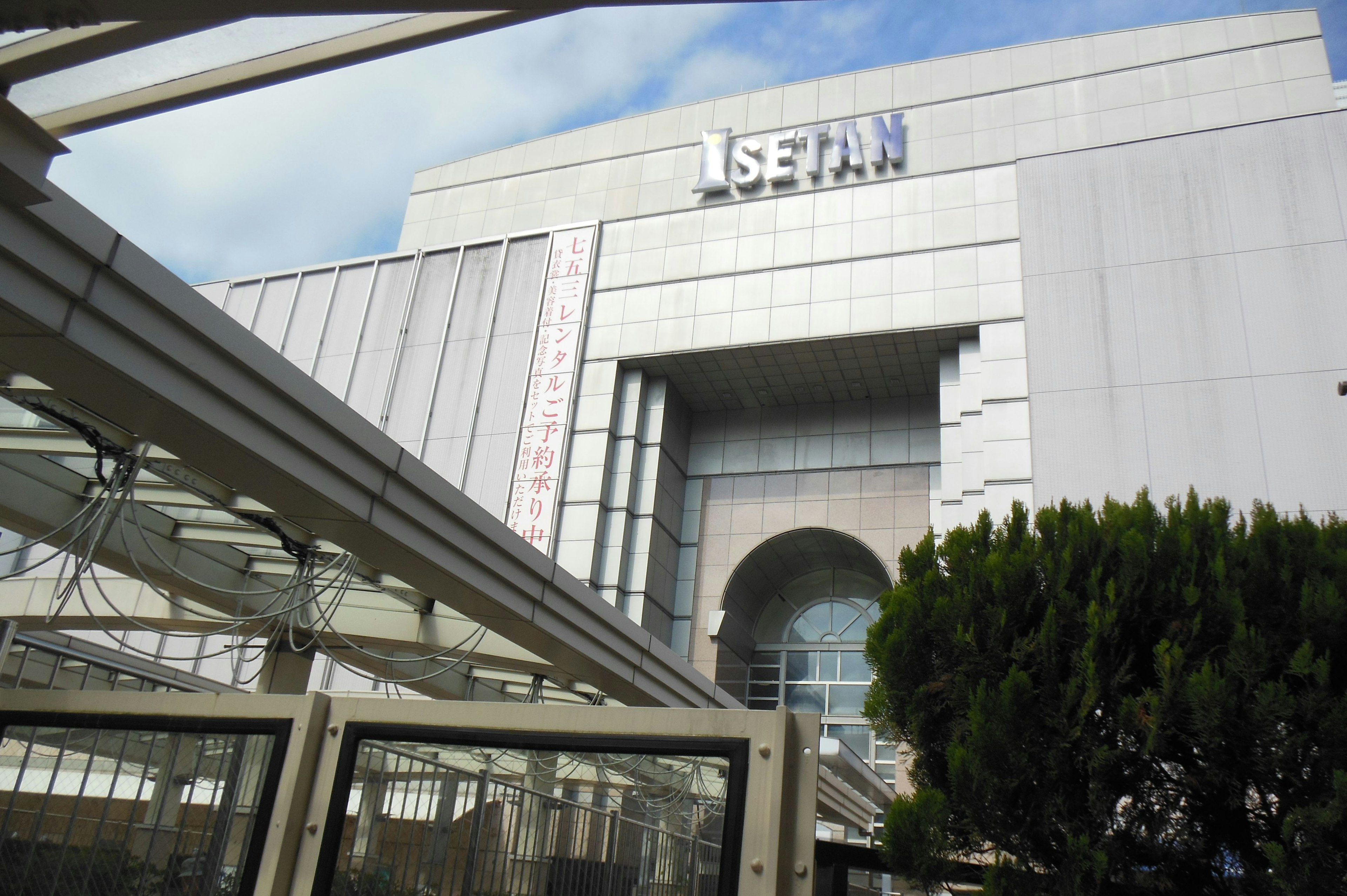 Vue extérieure du grand magasin Isetan avec une architecture moderne et une verdure environnante